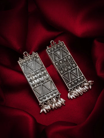 Decorative silver earrings on a red fabric background