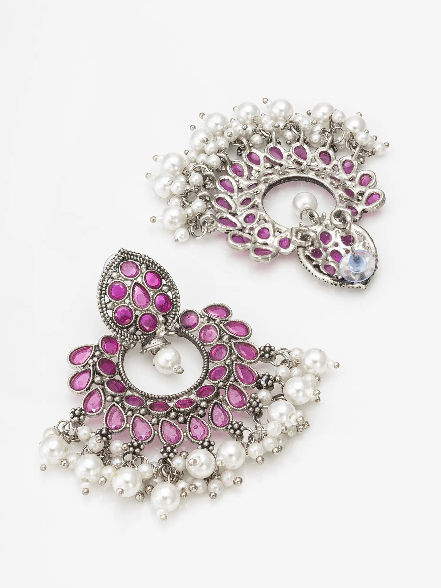Pair of ornate earrings with pink gemstones and pearl accents on a white background