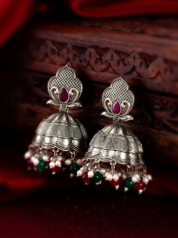 Silver jhumka earrings with red and green beads on a dark background