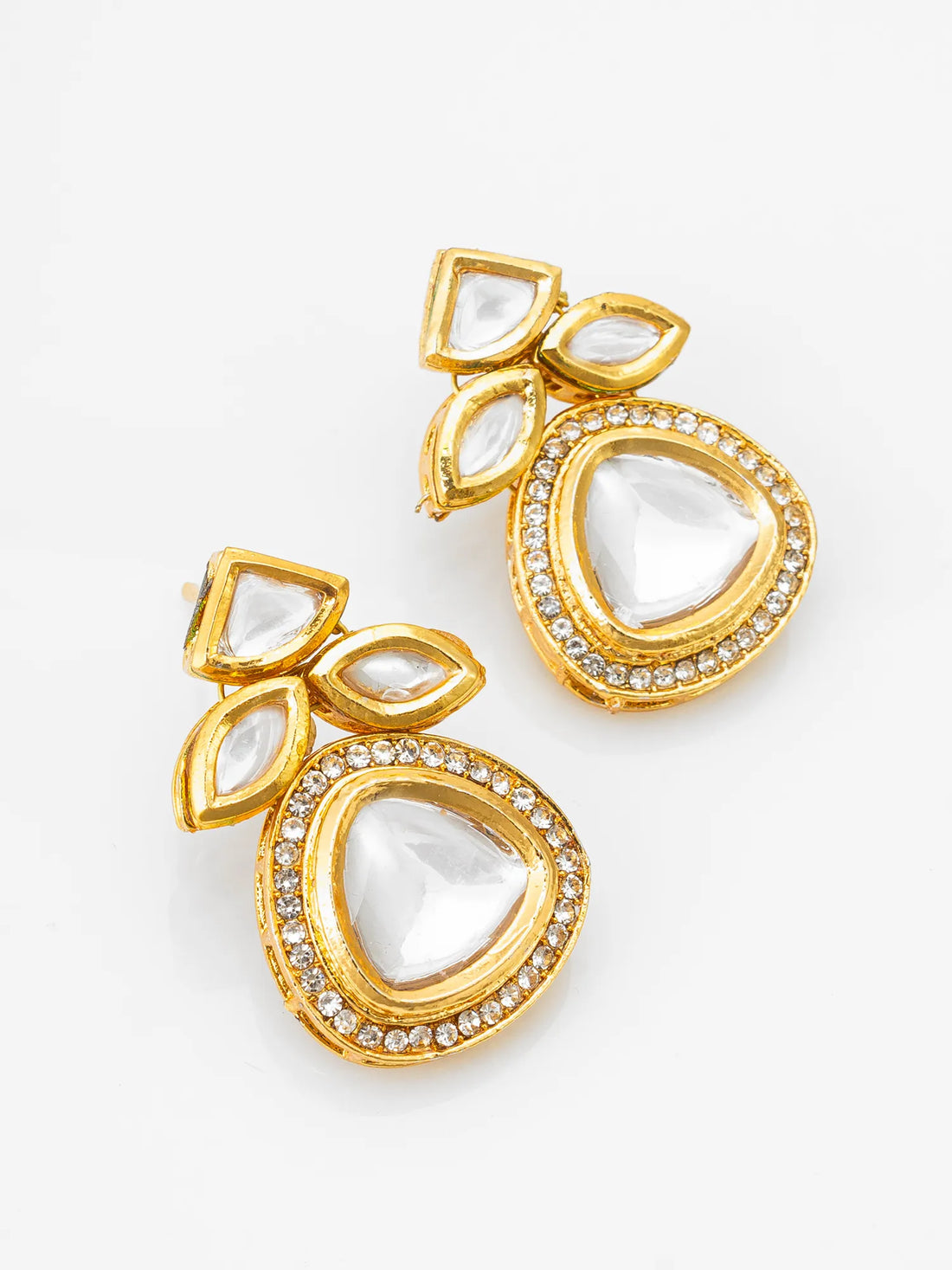 Gold earrings with heart-shaped gemstones on a red fabric background
