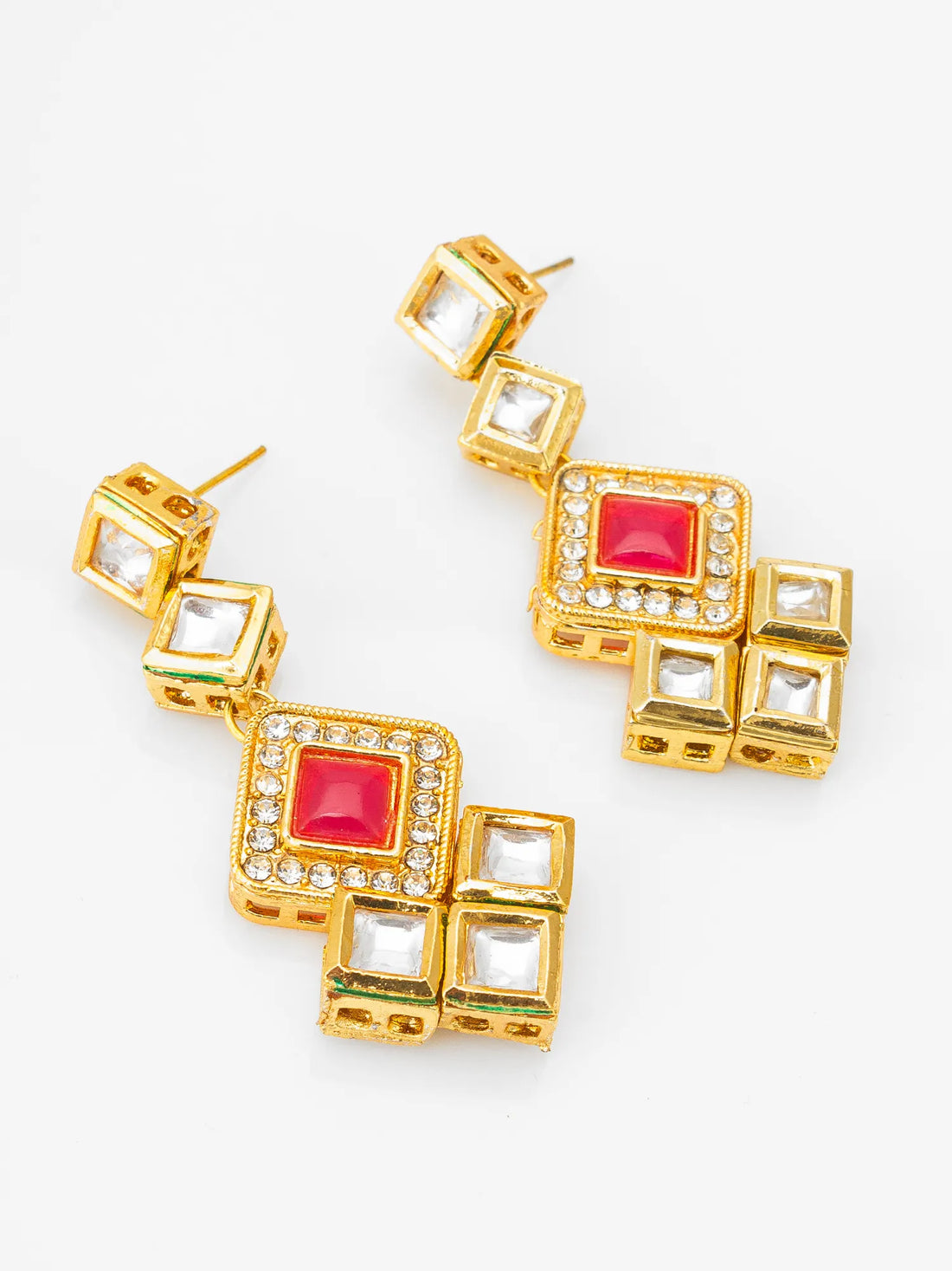 Gold earrings with red and clear gemstones on a red fabric background