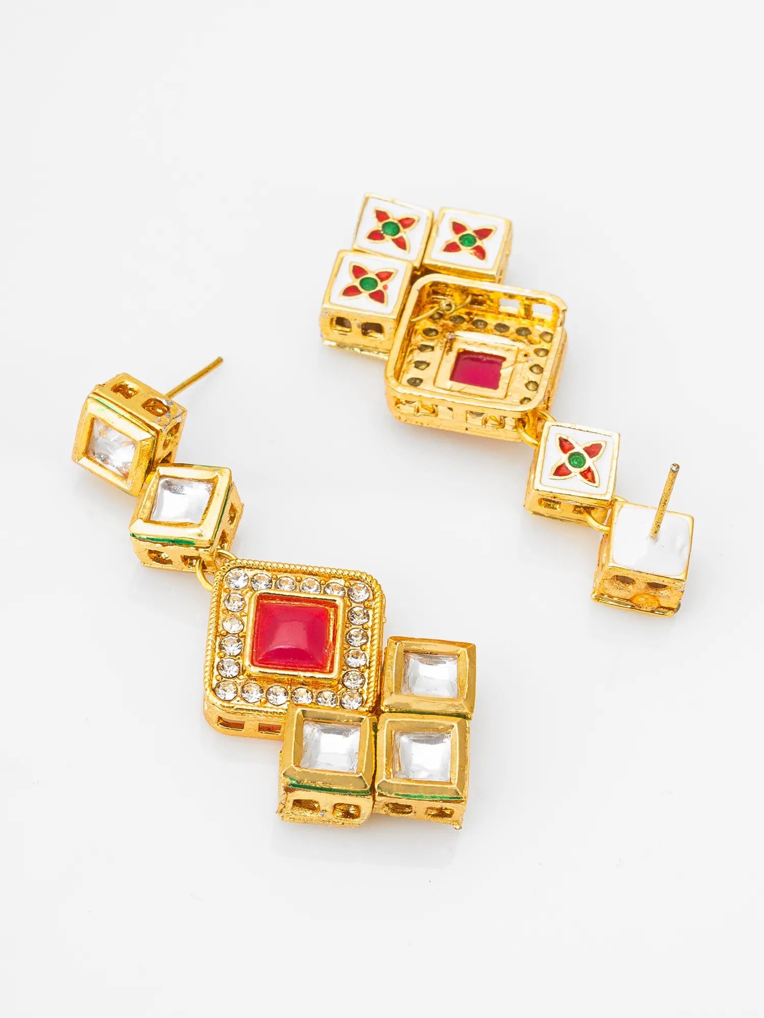 A pair of gold-plated Indian Kundan earrings with white enamel, red and green stone accents, and clear crystals, displayed on a clean white background.