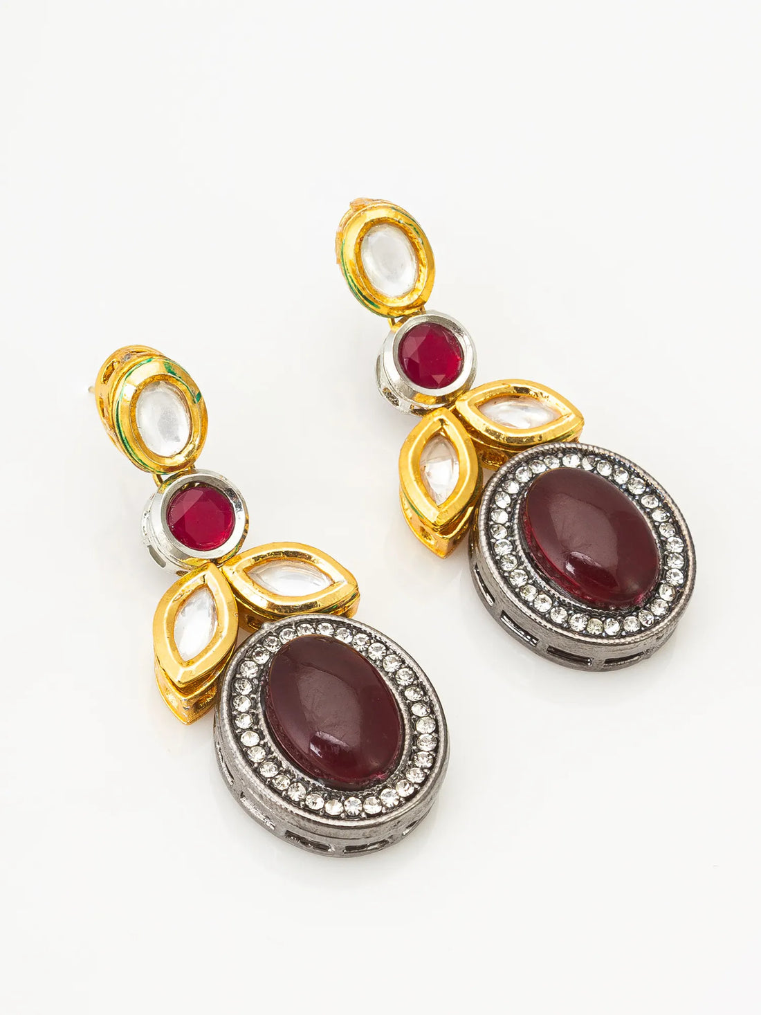 Gold earrings with red and clear gemstones on a red fabric background