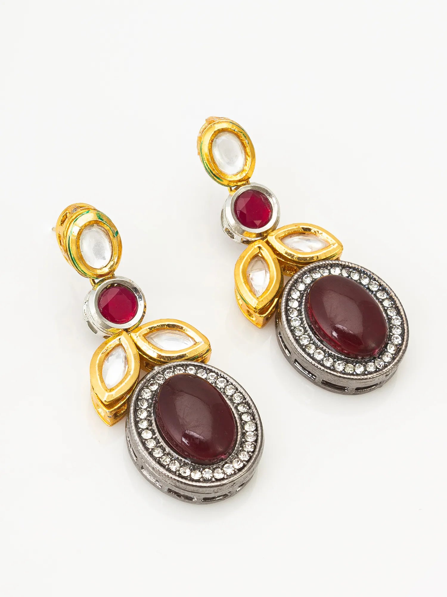 A pair of gold and silver drop earrings with oval deep red gemstones and small clear stones, shown on a plain white background.