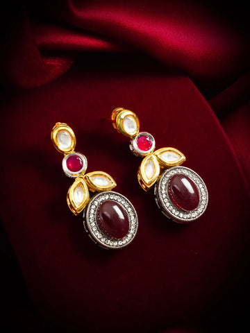 Gold earrings with red and clear gemstones on a red fabric background