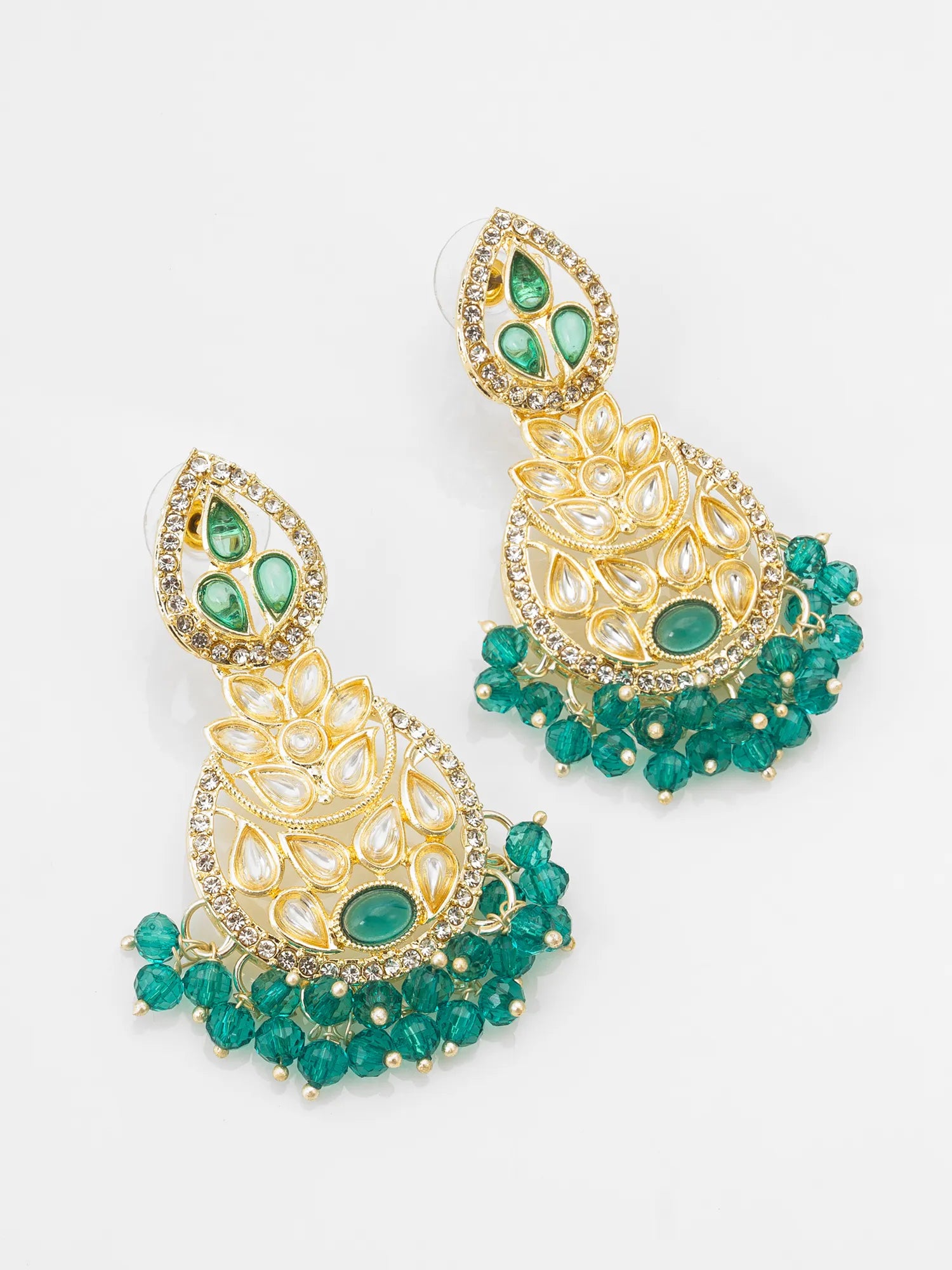 A pair of gold-plated Indian jhumka earrings embellished with green stones and small clear crystals, displayed on a clean white background.