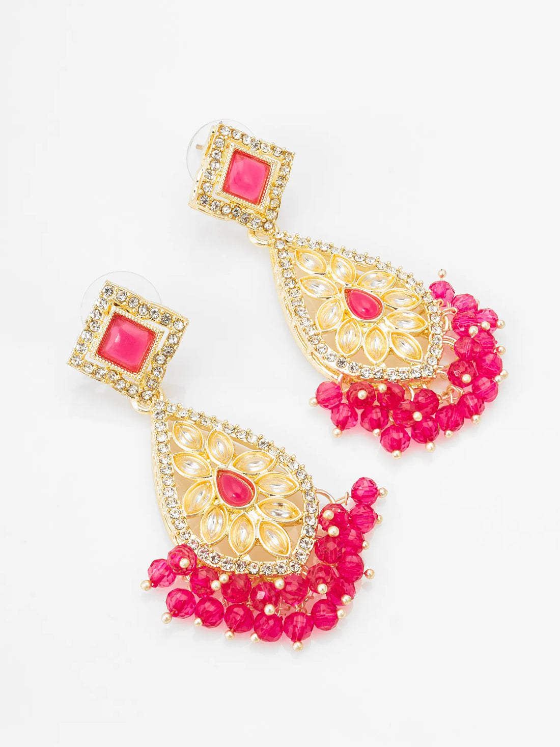Ornate gold and red earrings on a teal background