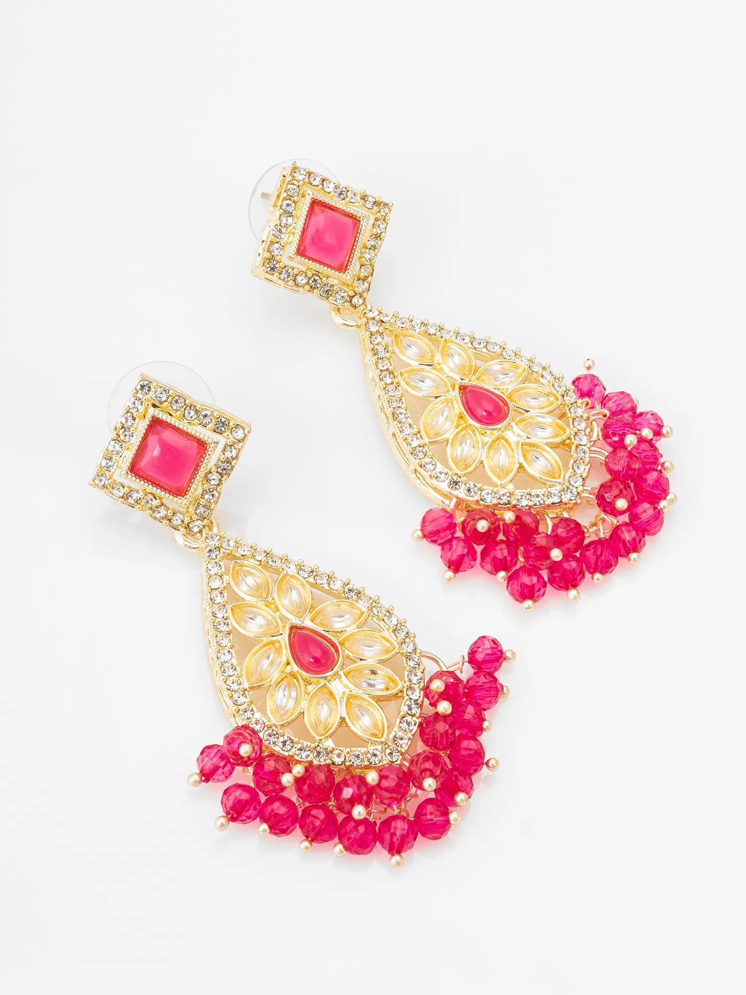 A pair of gold-plated Indian-style dangle earrings with bright pink stones and crystal embellishments, displayed on a clean white background.