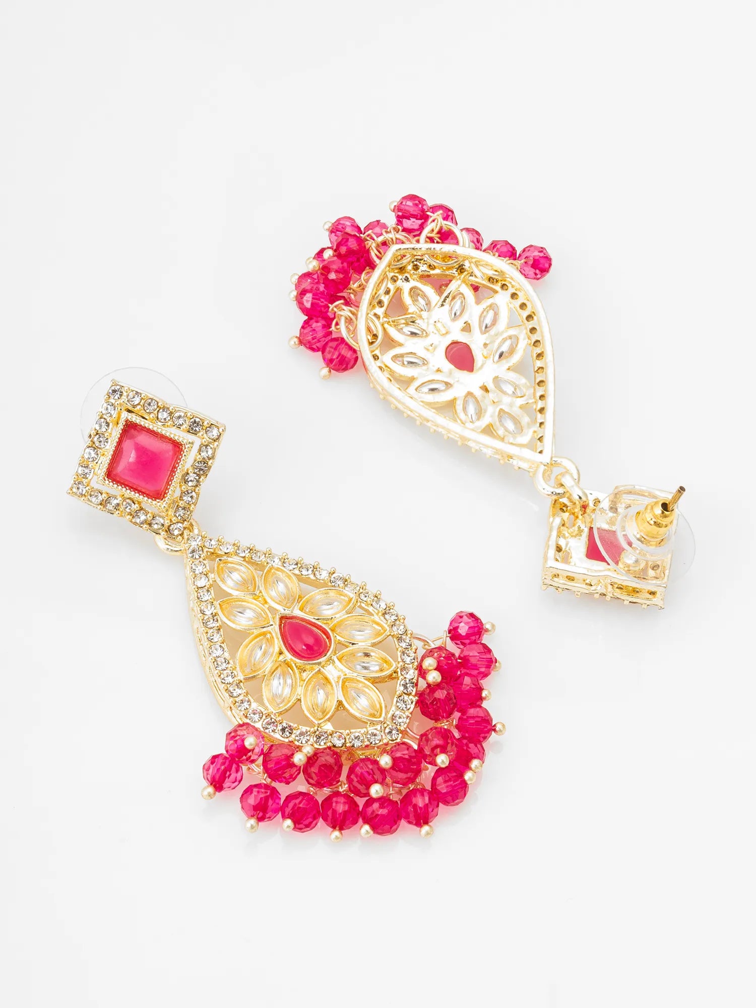 A pair of gold-plated traditional Indian jhumka earrings decorated with bright pink stones and crystal embellishments, displayed on a clean white background.