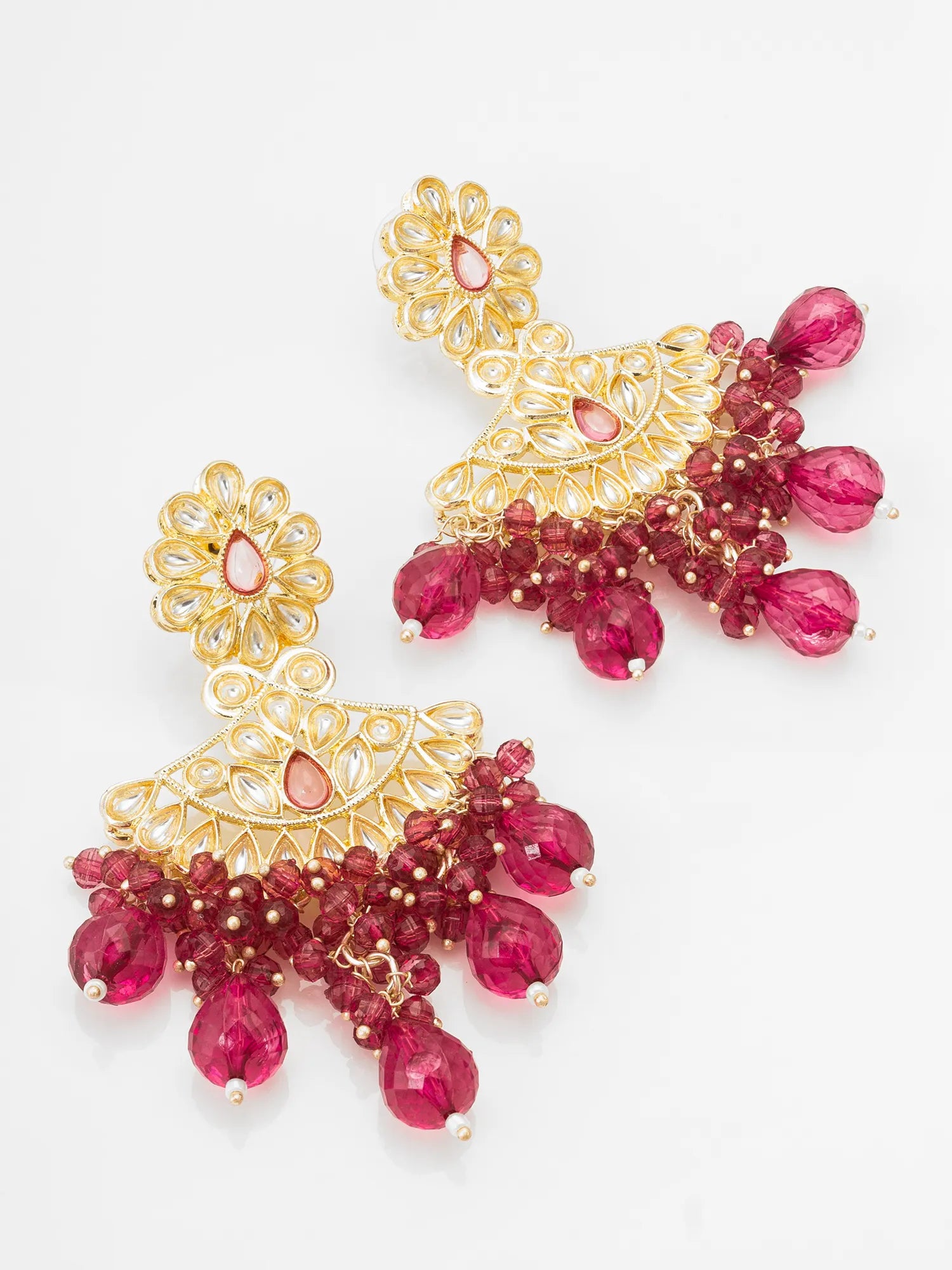 A pair of ornate gold-toned dangle earrings decorated with faceted deep pink gemstones and small pearl-like beads, displayed on a clean white background.