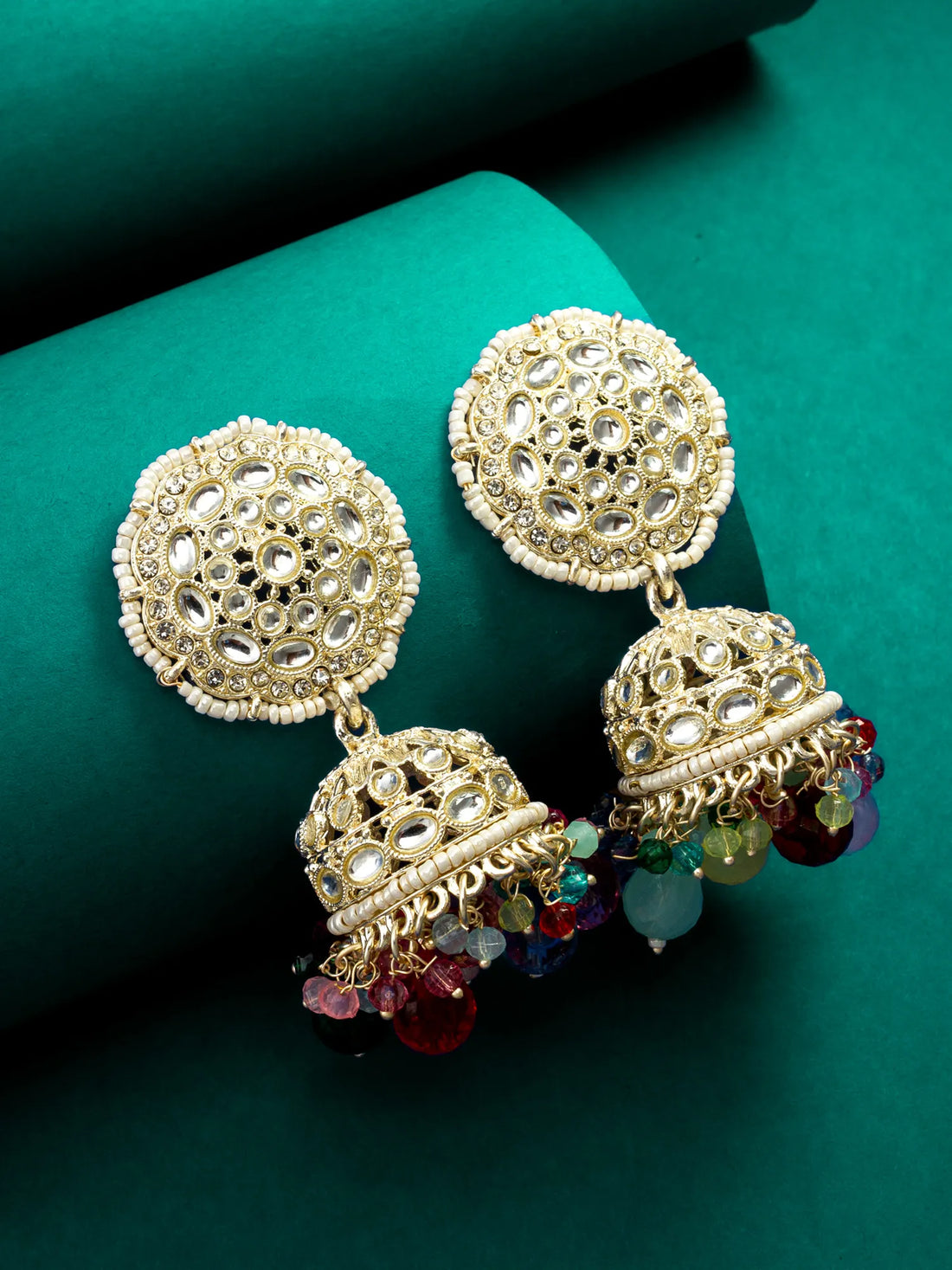 Gold earrings with intricate designs and colorful beads on a green background