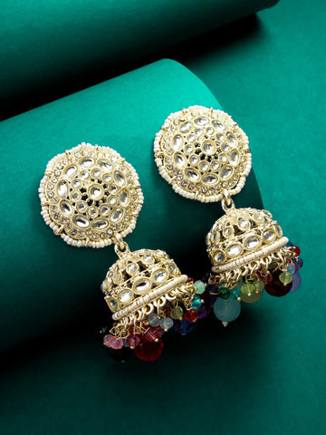 Gold earrings with intricate designs and colorful beads on a green background