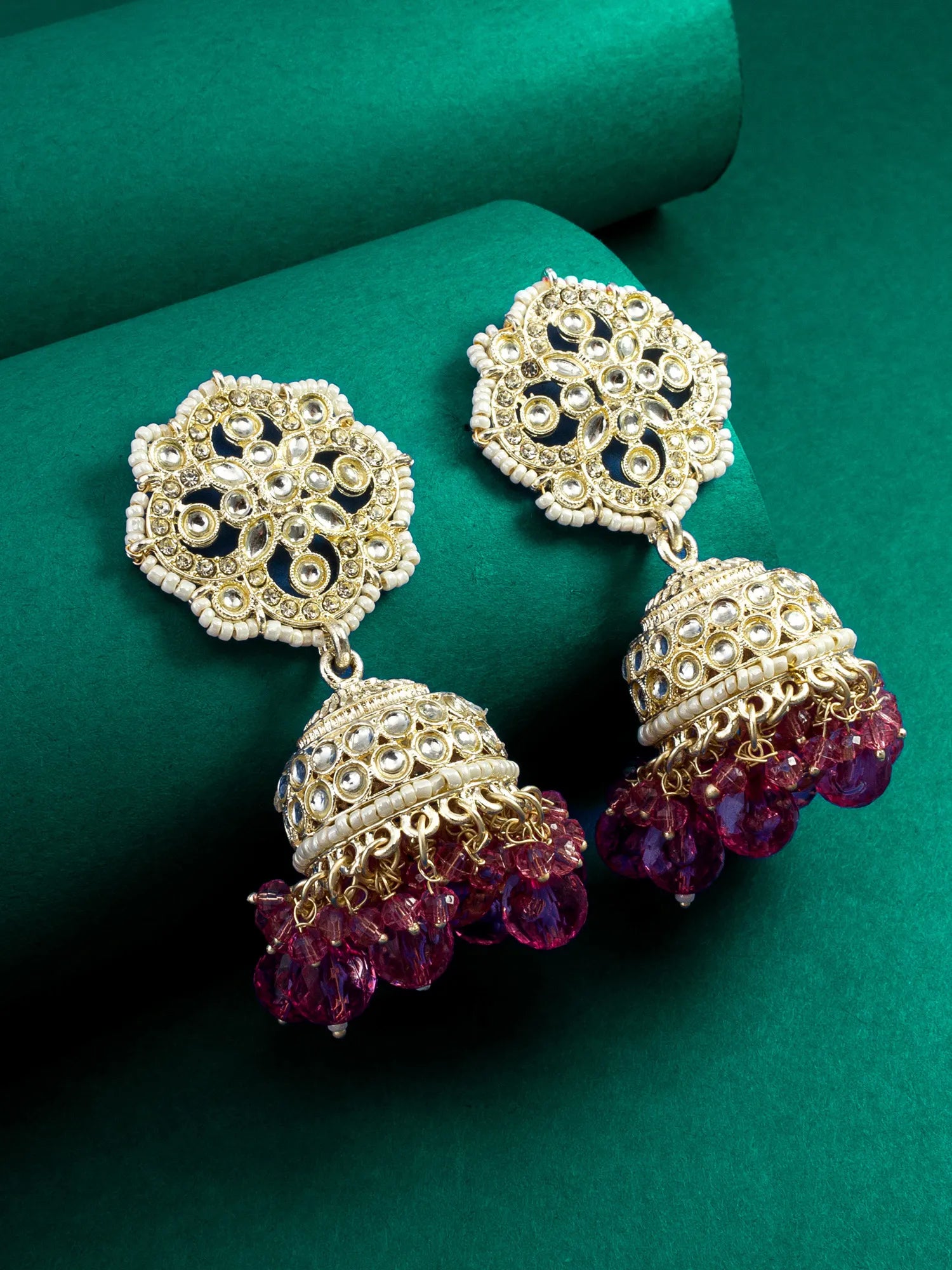 Ornate gold and purple earrings on a green background