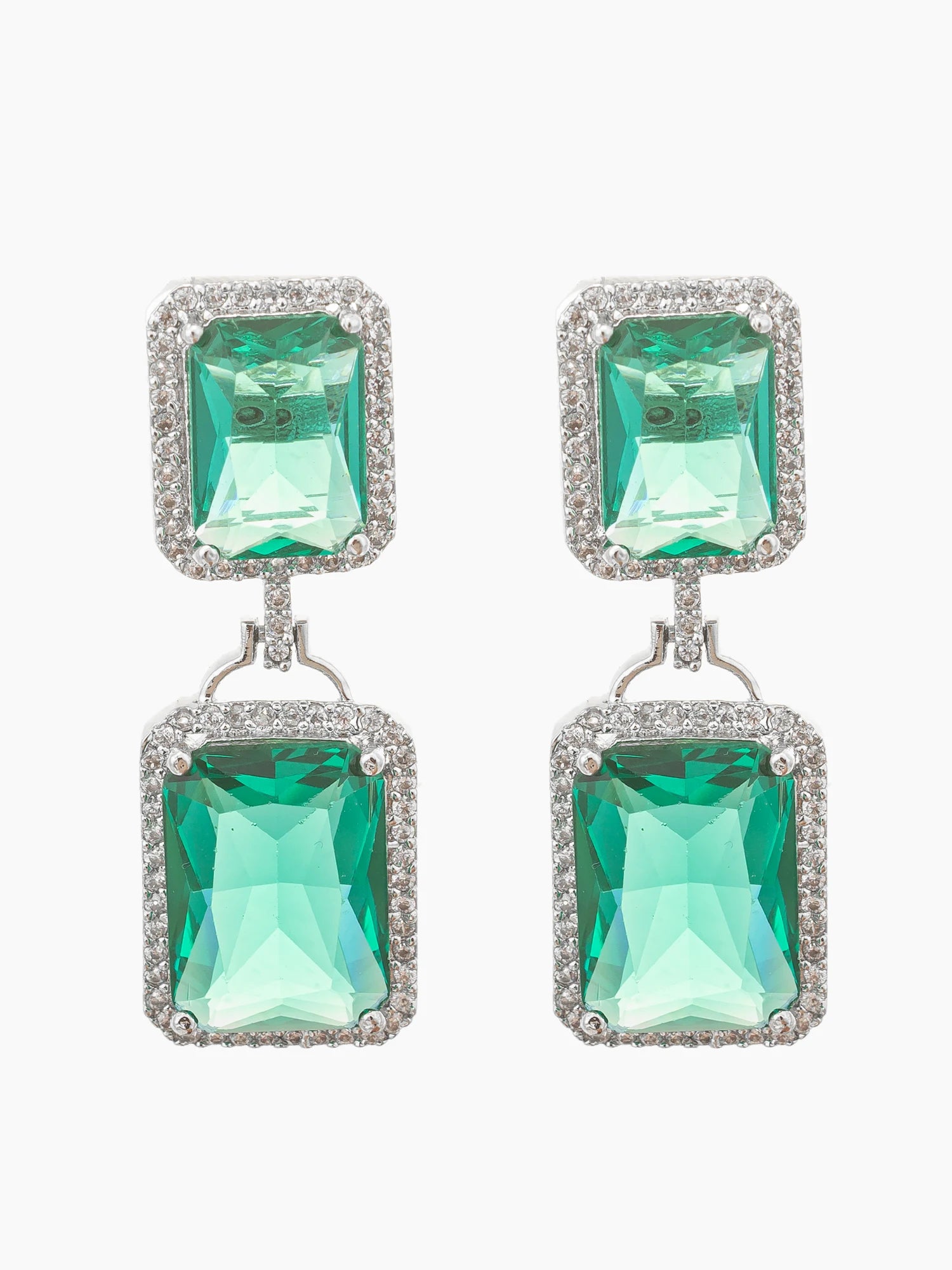 A pair of drop earrings featuring large rectangular emerald-cut green crystals surrounded by small clear stones, suspended from silver-toned posts on a light gray background.