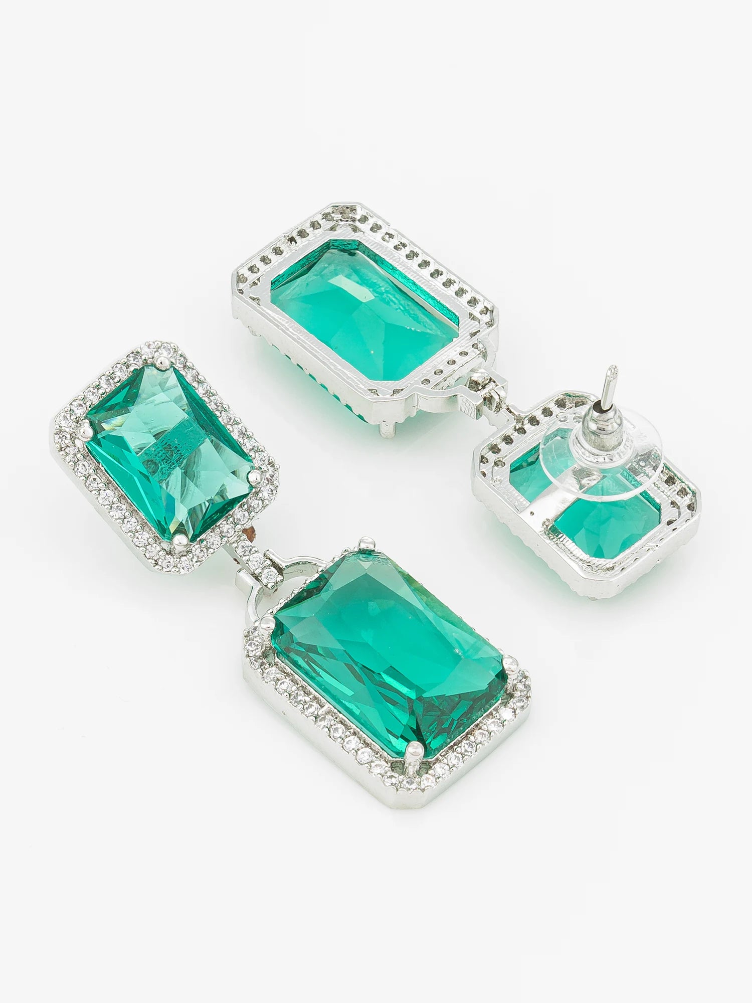 A pair of silver-tone drop earrings with rectangular emerald-cut green gemstones surrounded by small clear crystals, shown on a plain light background.