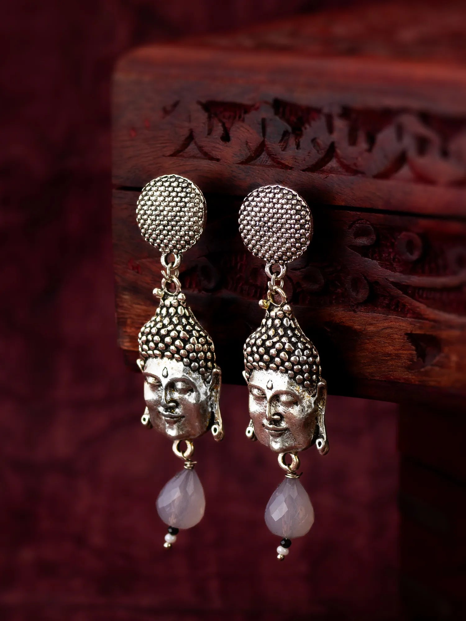 Silver Buddha Face Drop Earrings On A Background