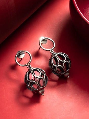 Oxidized Silver Cutwork Ball Drop Earrings On A Red Background