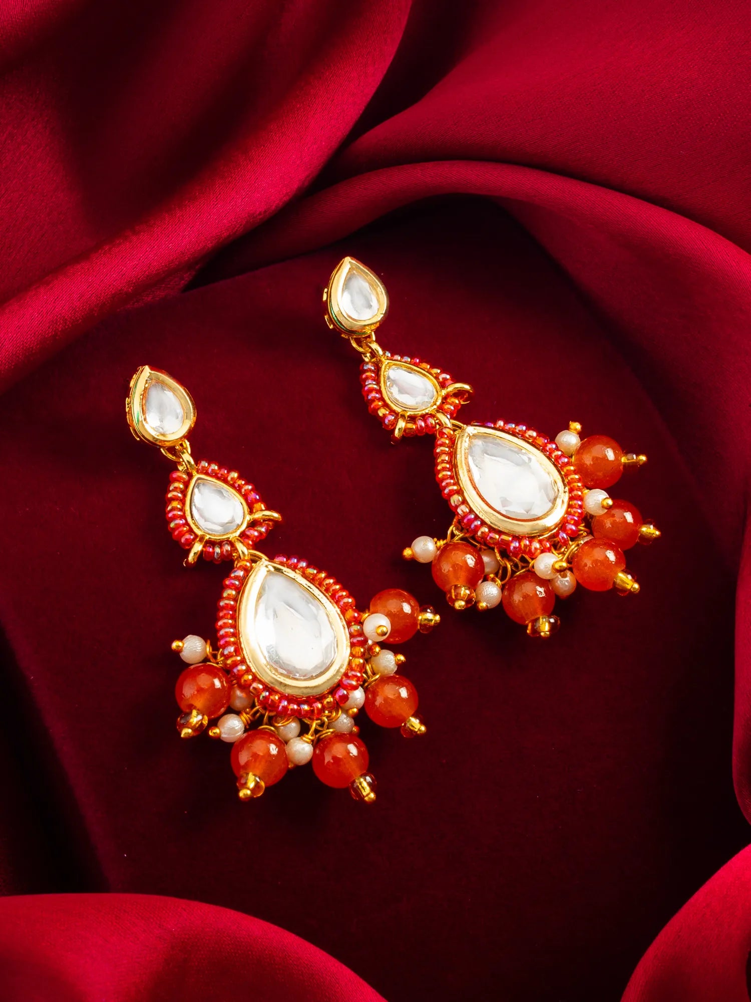 Gold-Toned Kundan Earrings On A Red Background