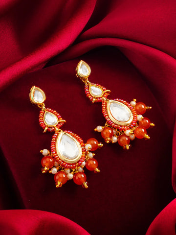 Gold-Toned Kundan Earrings On A Red Background