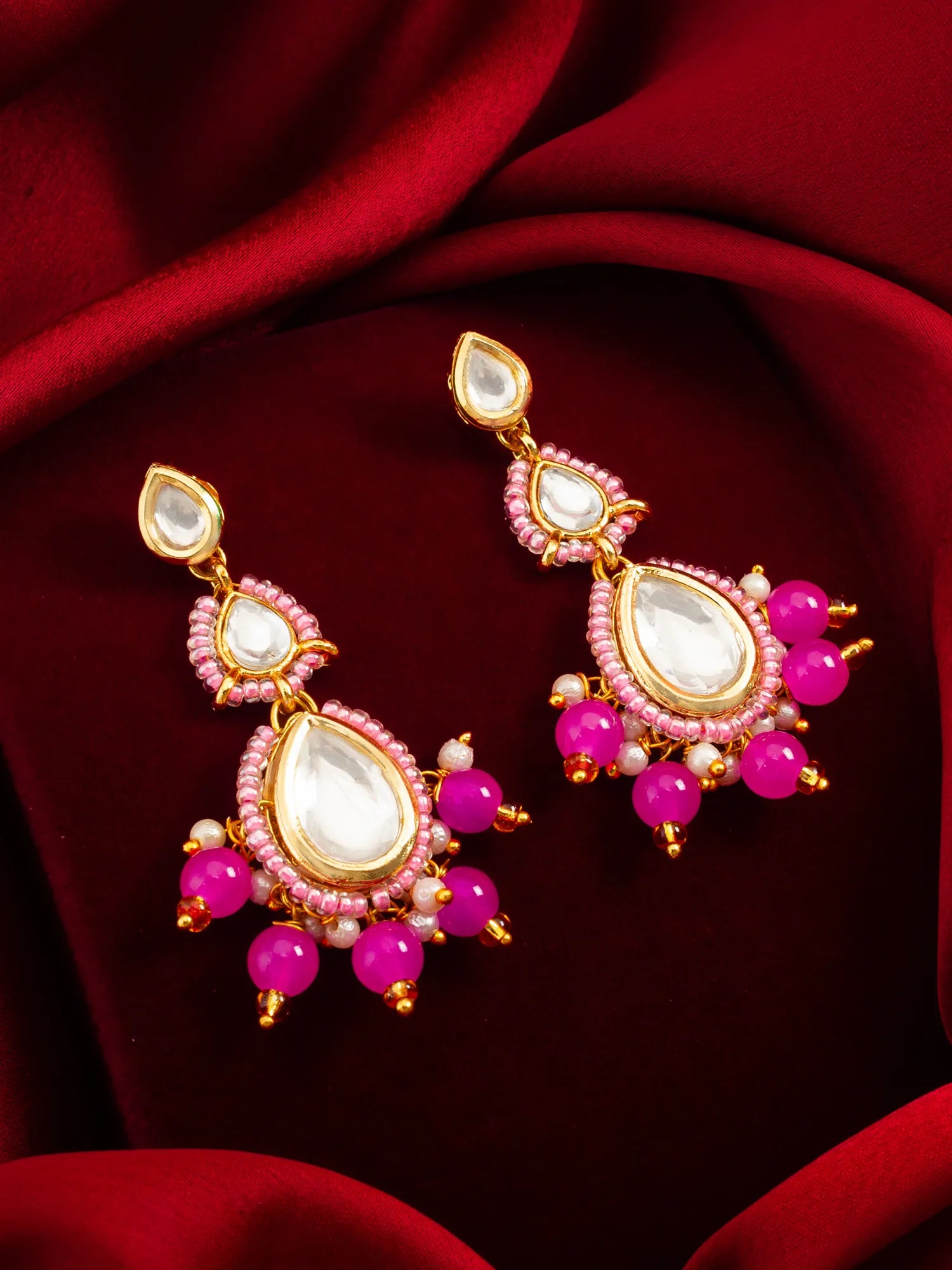 Pink Kundan Beaded Drop Earrings On A Red Background