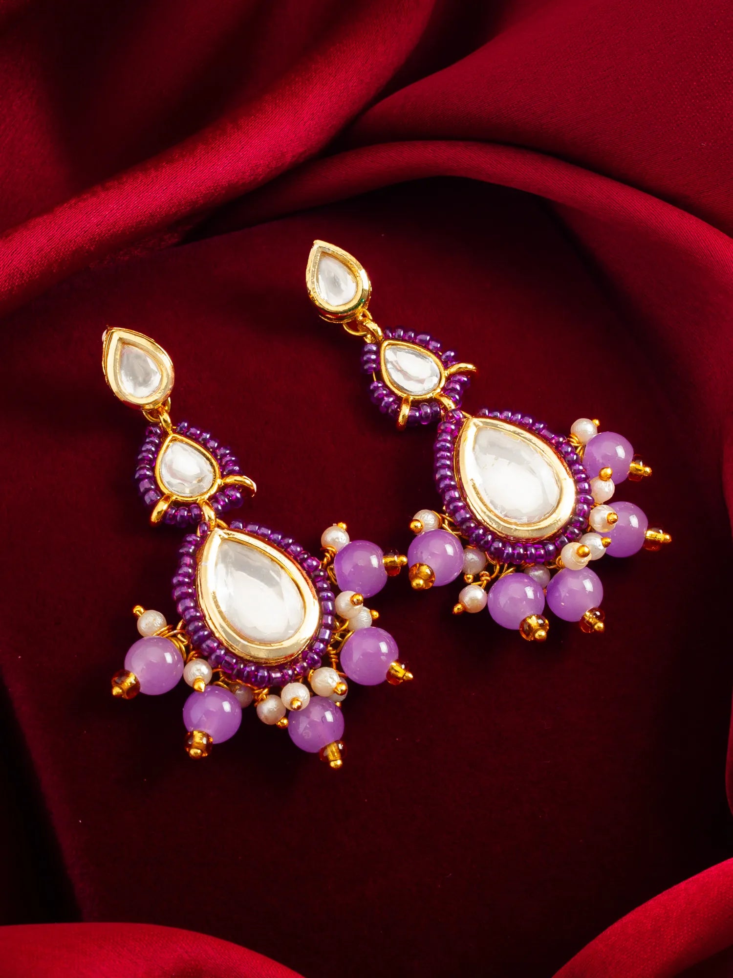 Purple Kundan Beaded Drop Earrings On A Red Background