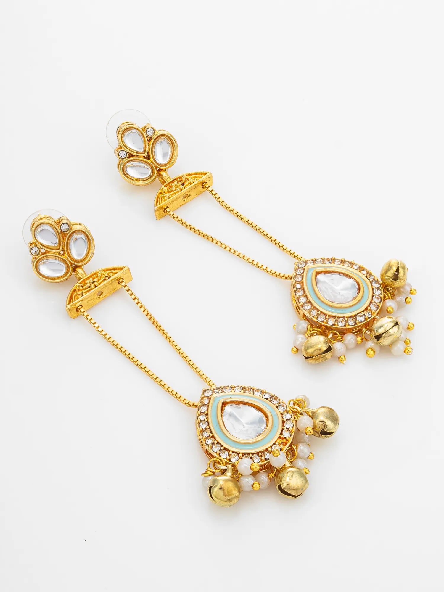 A pair of gold-toned Indian-style dangle earrings with teardrop-shaped white stone centers, light blue enamel accents, small white pearls, and dangling gold bells, shown on a plain white background.