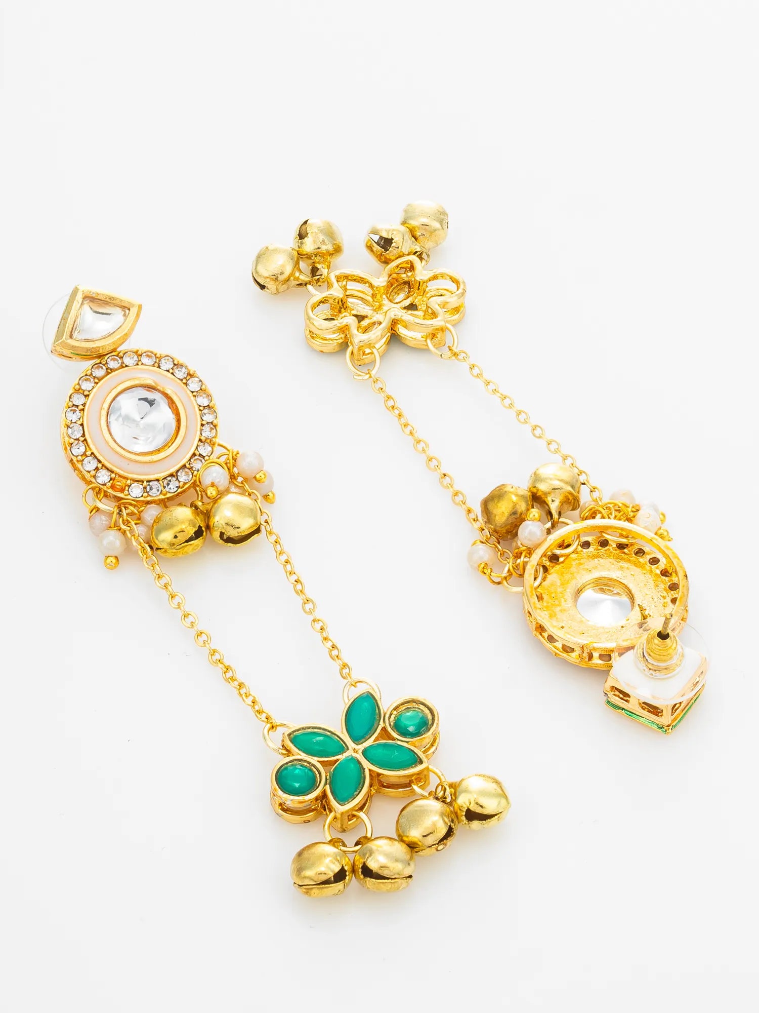 A pair of gold-toned Indian style earrings decorated with green stone accents, small white stones, and tiny gold bells, displayed on a clean white background.