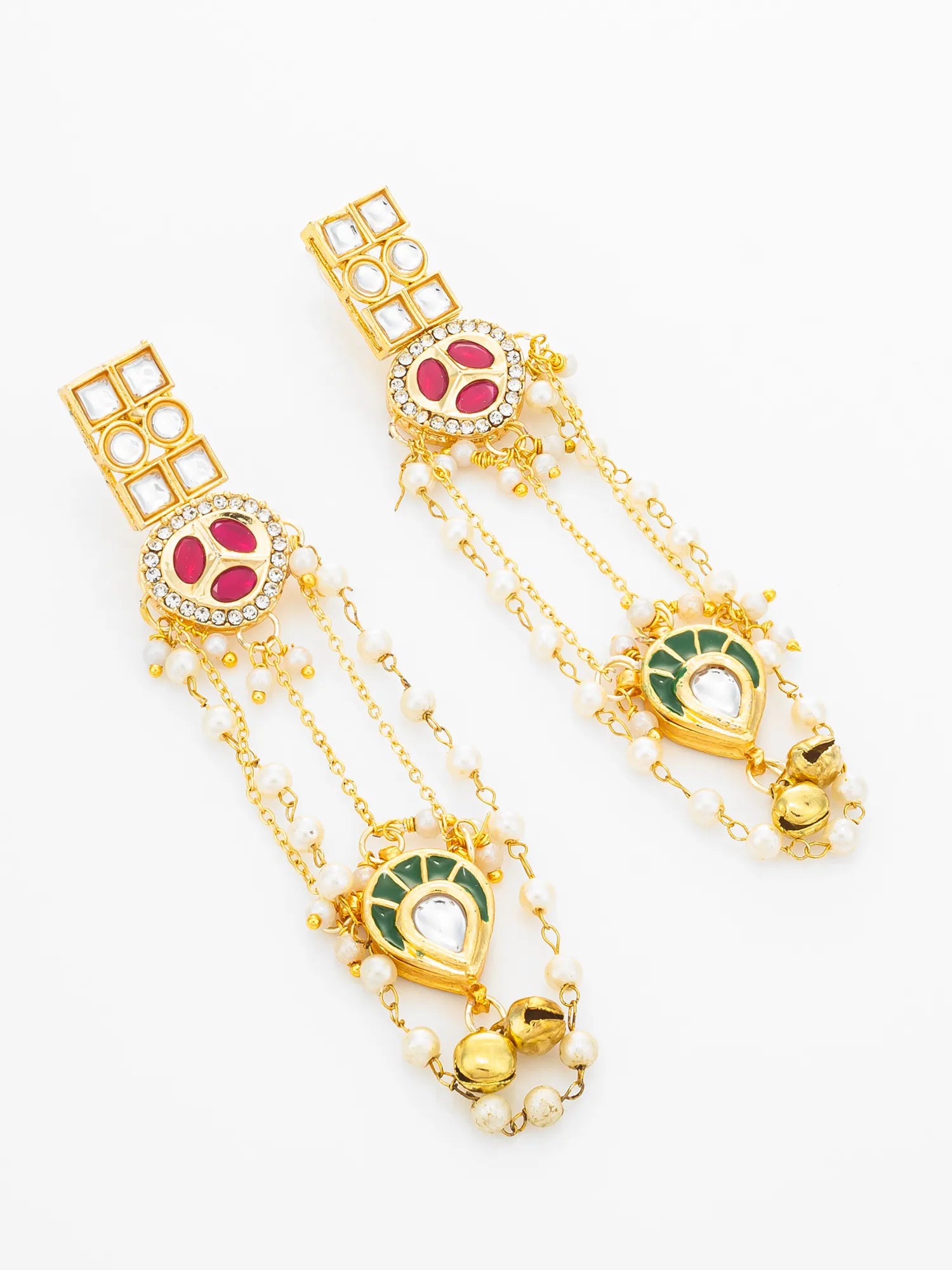 A pair of gold-toned traditional Indian earrings with red and green enamel details, white bead chains, and small crystal accents, displayed on a clean white background.