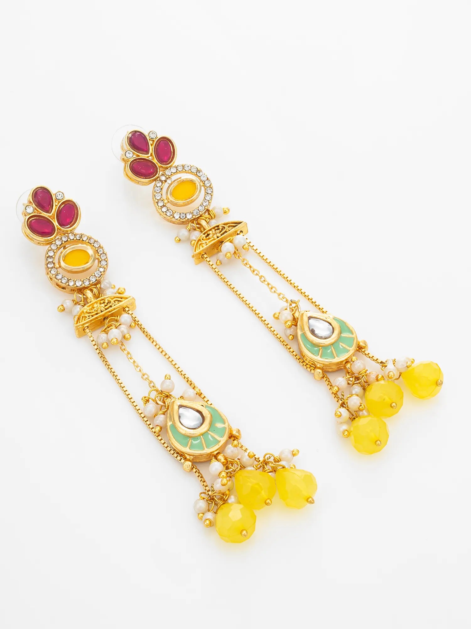 A pair of gold-plated Indian style dangle earrings with yellow beads, green enamel, and red stone accents, displayed on a clean white background.