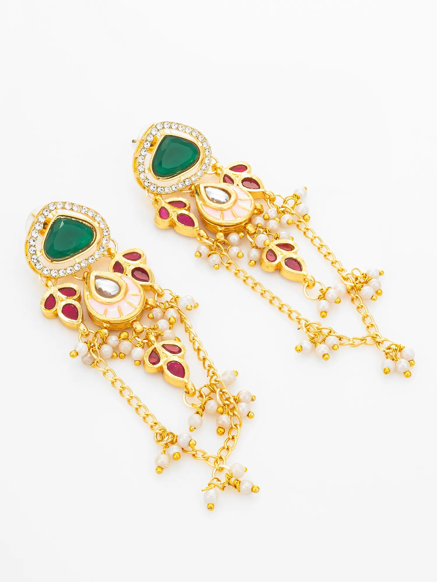 A pair of gold-toned Indian jhumka earrings decorated with a green teardrop stone, white pearl-like beads, and red enamel details, set against a plain white background.
