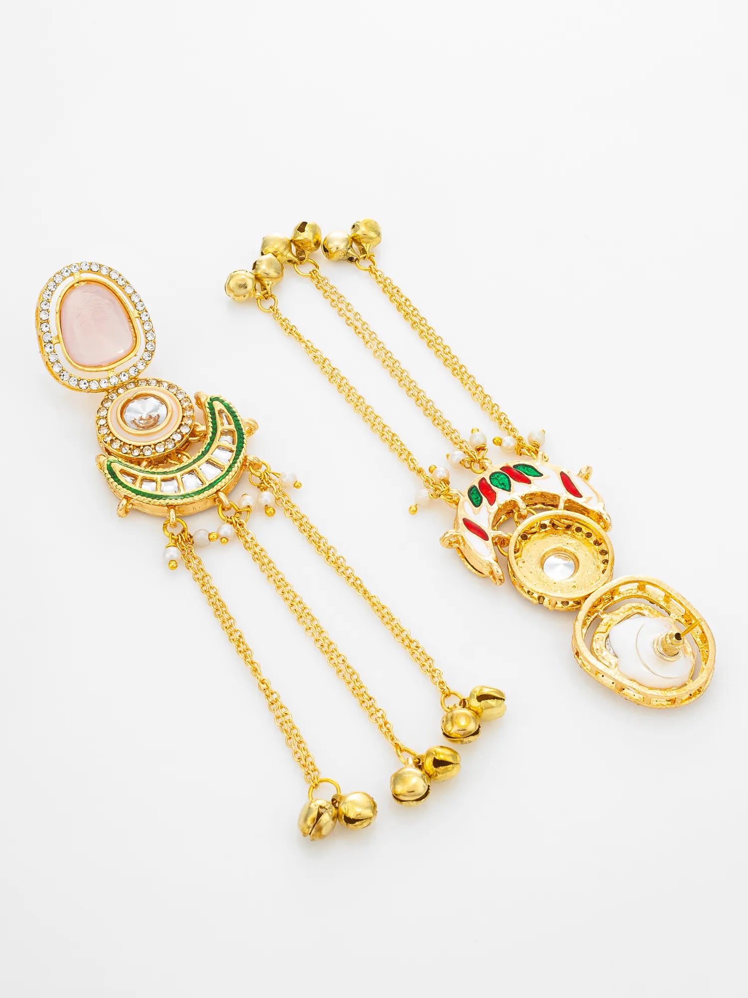 A pair of gold-toned traditional Indian dangle earrings with intricate engravings, pink stone accents, green and red enamel details, and dangling chain ends with small gold bells, displayed on a clean white background.