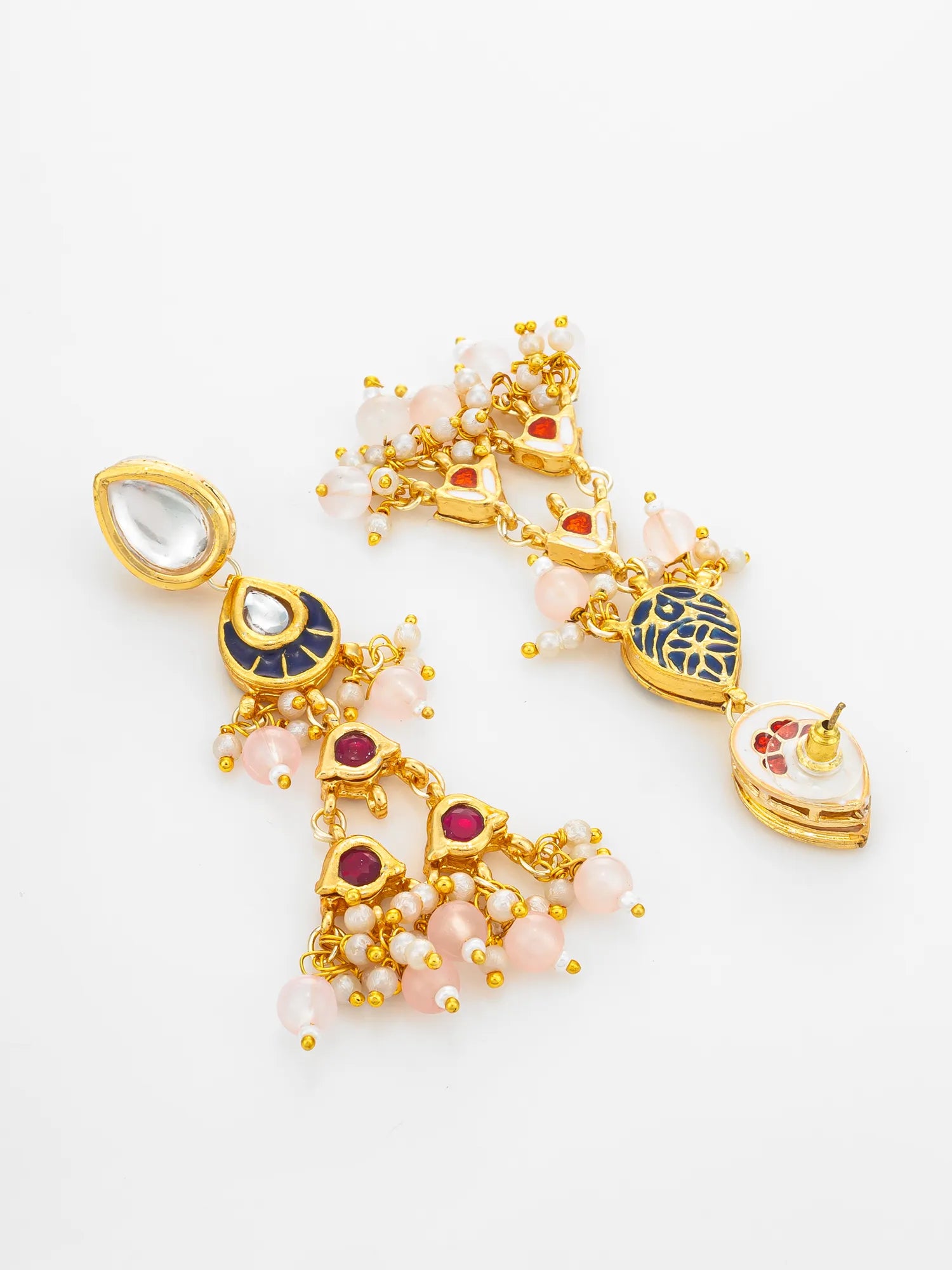 A pair of gold-toned Indian jhumka earrings decorated with light pink pearls, dark blue enamel, and red gemstones, displayed on a clean white background.