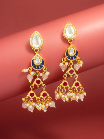 A pair of gold-plated dangle earrings with white stone tops, navy blue enamel sections, and pink pearl-like bead clusters, displayed on a curved pink background.