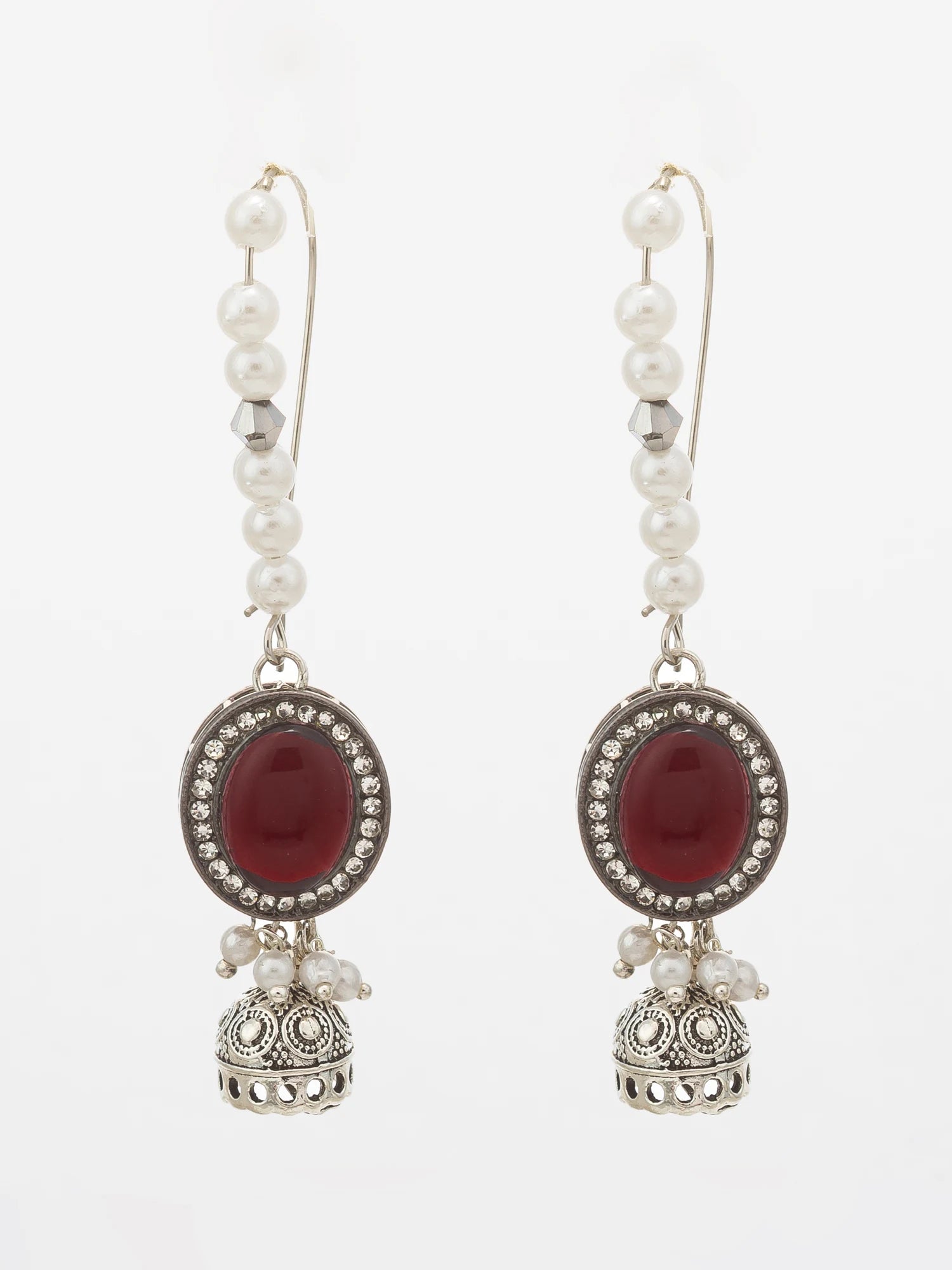 A pair of silver-toned dangle earrings featuring white pearl beads, oval red gemstones, and ornate silver bell-shaped charms, set against a plain white background.
