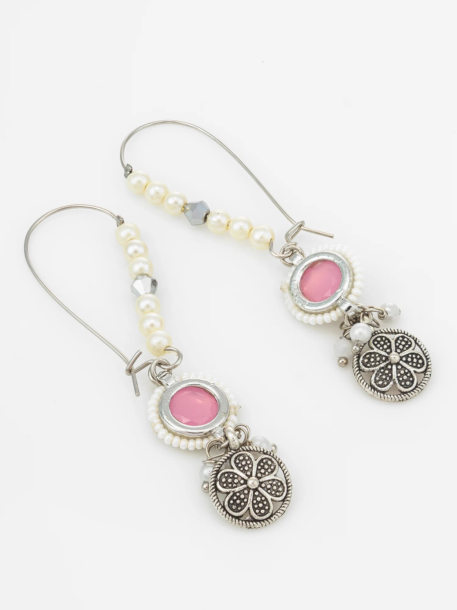 A pair of silver-toned dangle earrings with white faux pearls, pink oval stones, and ornate filigree round charms, shown on a plain white background.