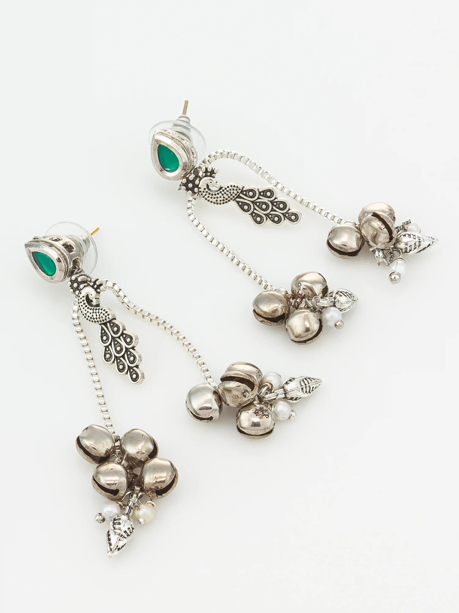 A pair of silver-toned dangle earrings with green teardrop-shaped stones, ornate filigree details, and clusters of small metallic bells and pearl-like beads, displayed on a clean white background.