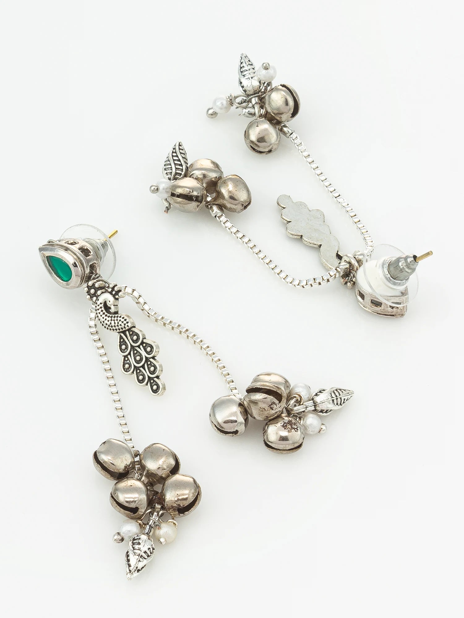A pair of silver-toned dangle earrings with a green teardrop stone, silver beads, small silver bells, and decorative leaf and cloud charms, displayed on a clean white background.