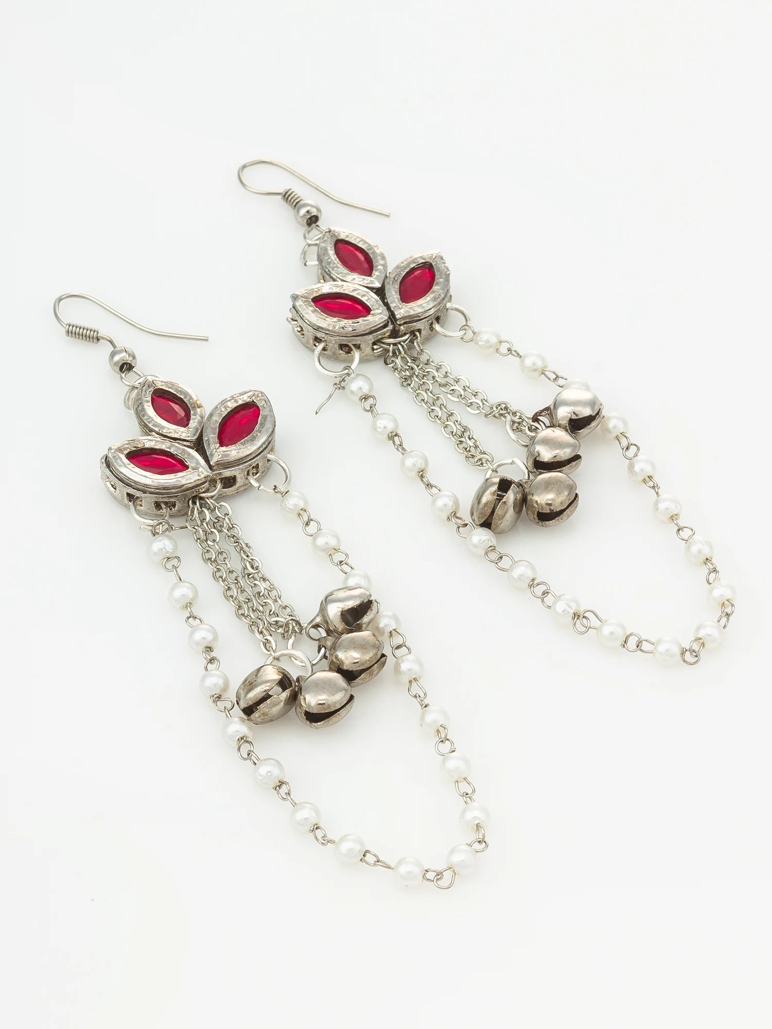 A pair of silver-toned dangle earrings with red marquise-cut stones and small silver bells on a white background.