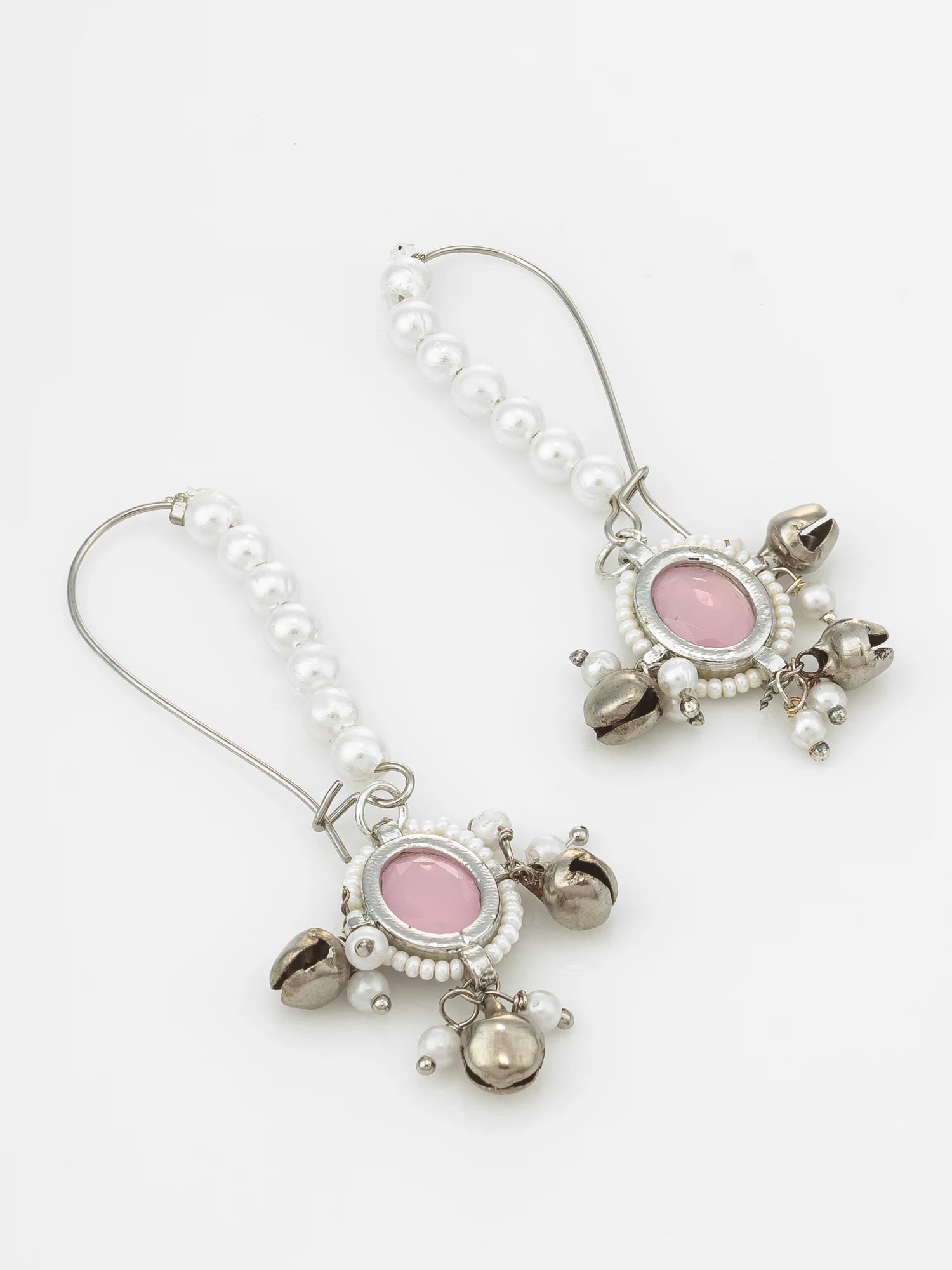A pair of silver-toned drop earrings featuring a vertical strand of white faux pearls, an oval pink stone centerpiece, and dangling silver bells, set against a light gray background.