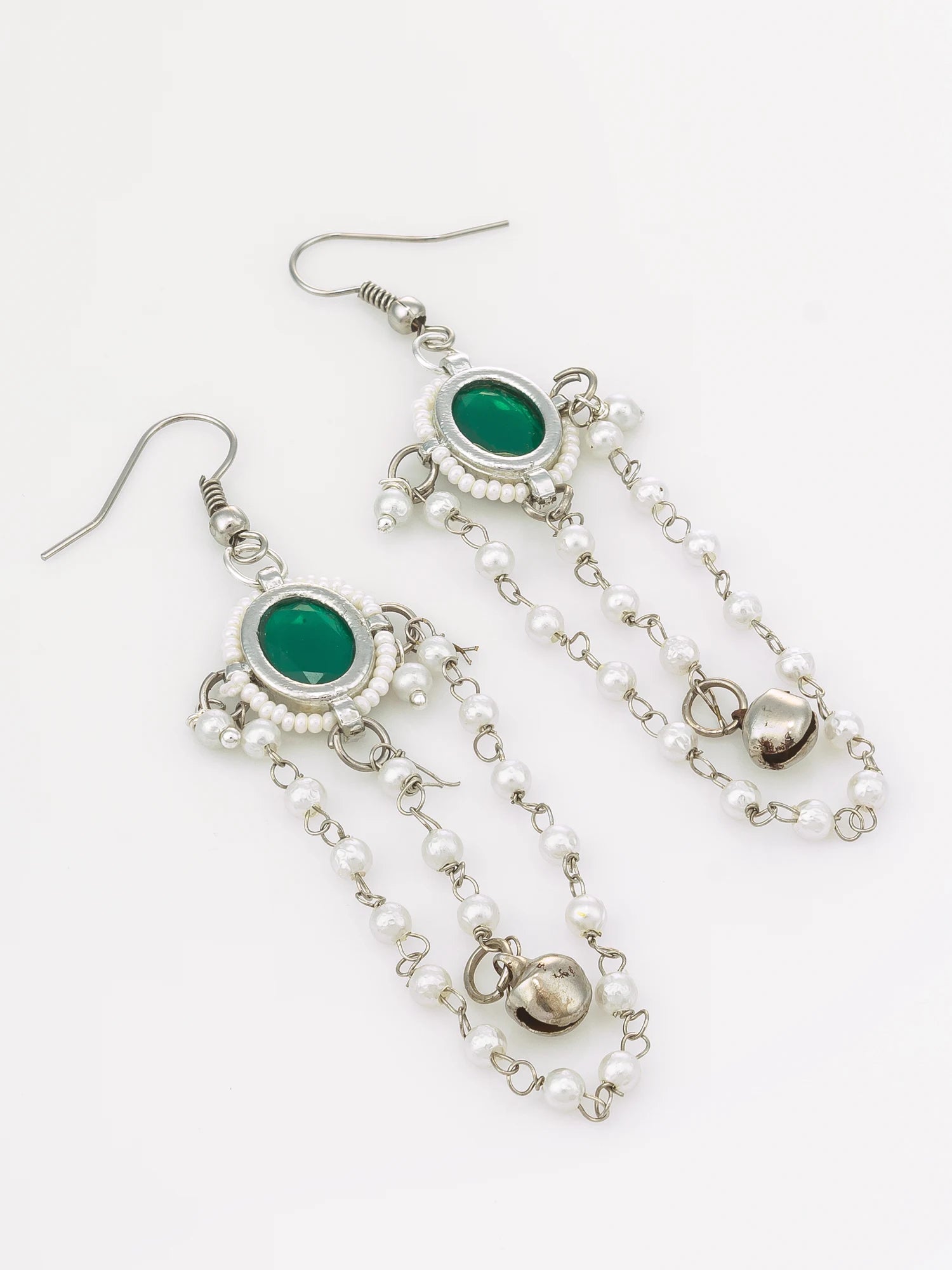 A pair of silver-toned dangle earrings featuring oval green stones, white pearl-like beads, and small metallic bells, displayed on a clean white background.