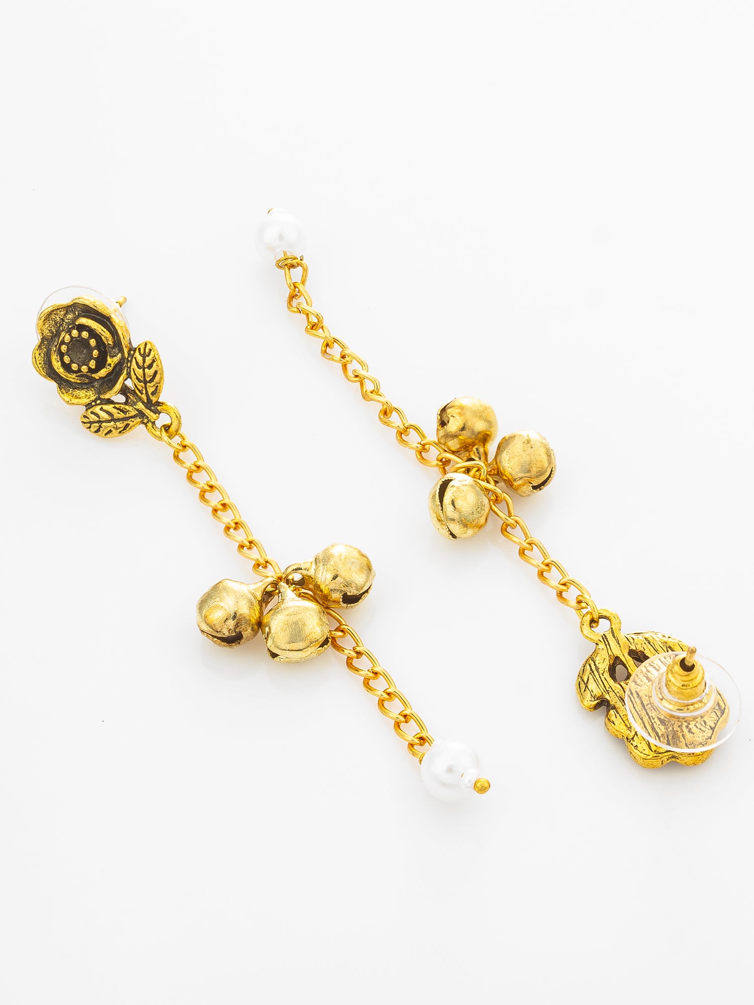 A pair of gold-toned traditional Indian earrings with floral motifs, small bells, and white pearl-like beads on a plain white background.