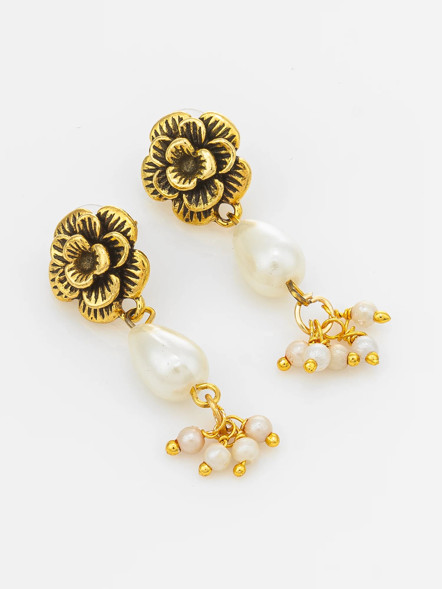 A pair of gold-toned dangle earrings featuring textured flower-shaped studs, a large pearl drop, and smaller pearl clusters at the bottom, shown on a plain white background.