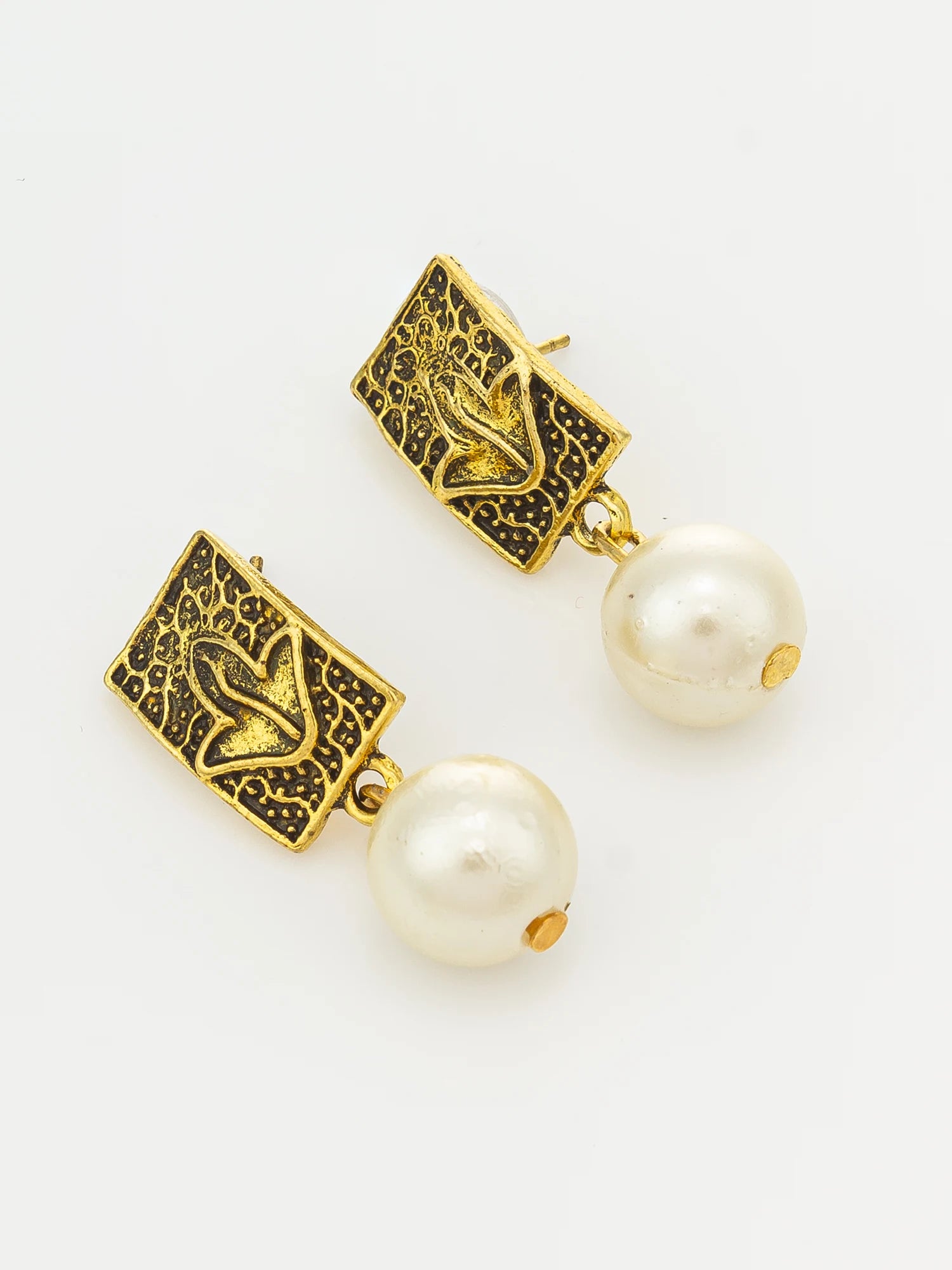A pair of gold and white drop earrings featuring textured square gold tops with a central leaf motif and hanging white pearl beads, shown on a clean white background.