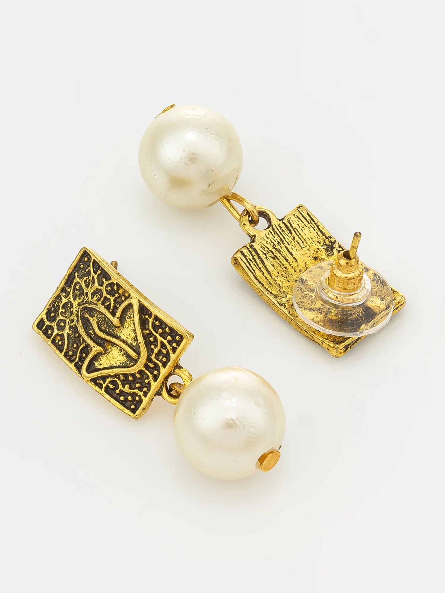 A pair of gold and white pearl drop earrings on a clean white background. One earring is shown from the front, featuring a textured gold square plate with a butterfly motif, while the other shows the back with a clear plastic fastener.