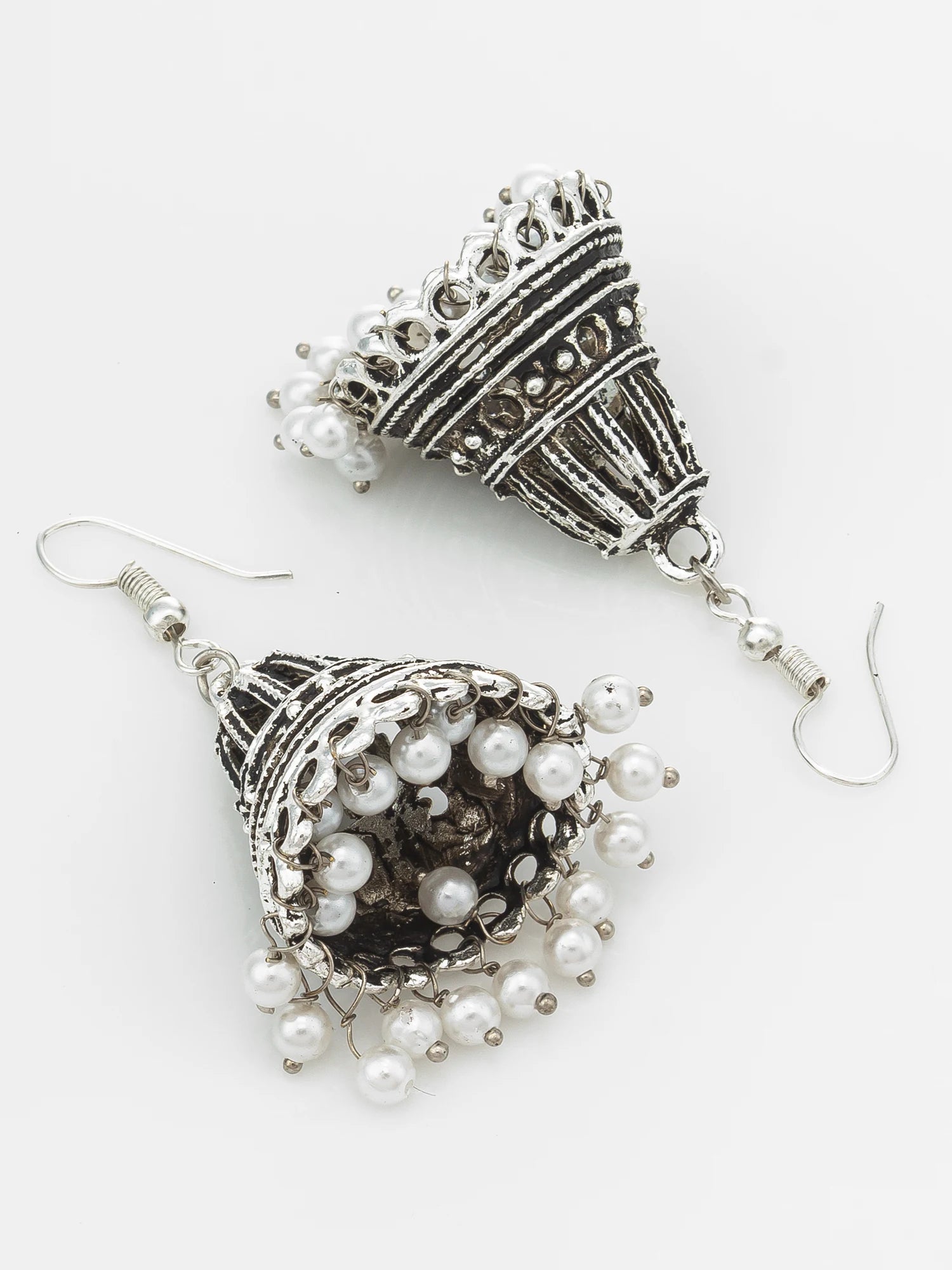 A pair of silver-toned jhumka earrings with intricate filigree detailing and dangling white faux pearl beads, displayed on a clean white background.