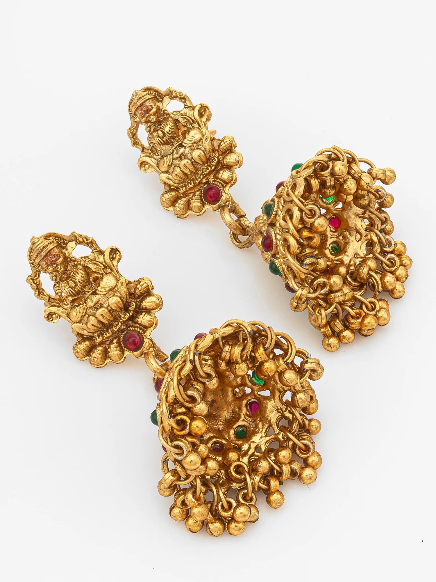 A pair of ornate gold-toned traditional earrings with intricate filigree detailing and small red and green stone accents, displayed on a clean white background.