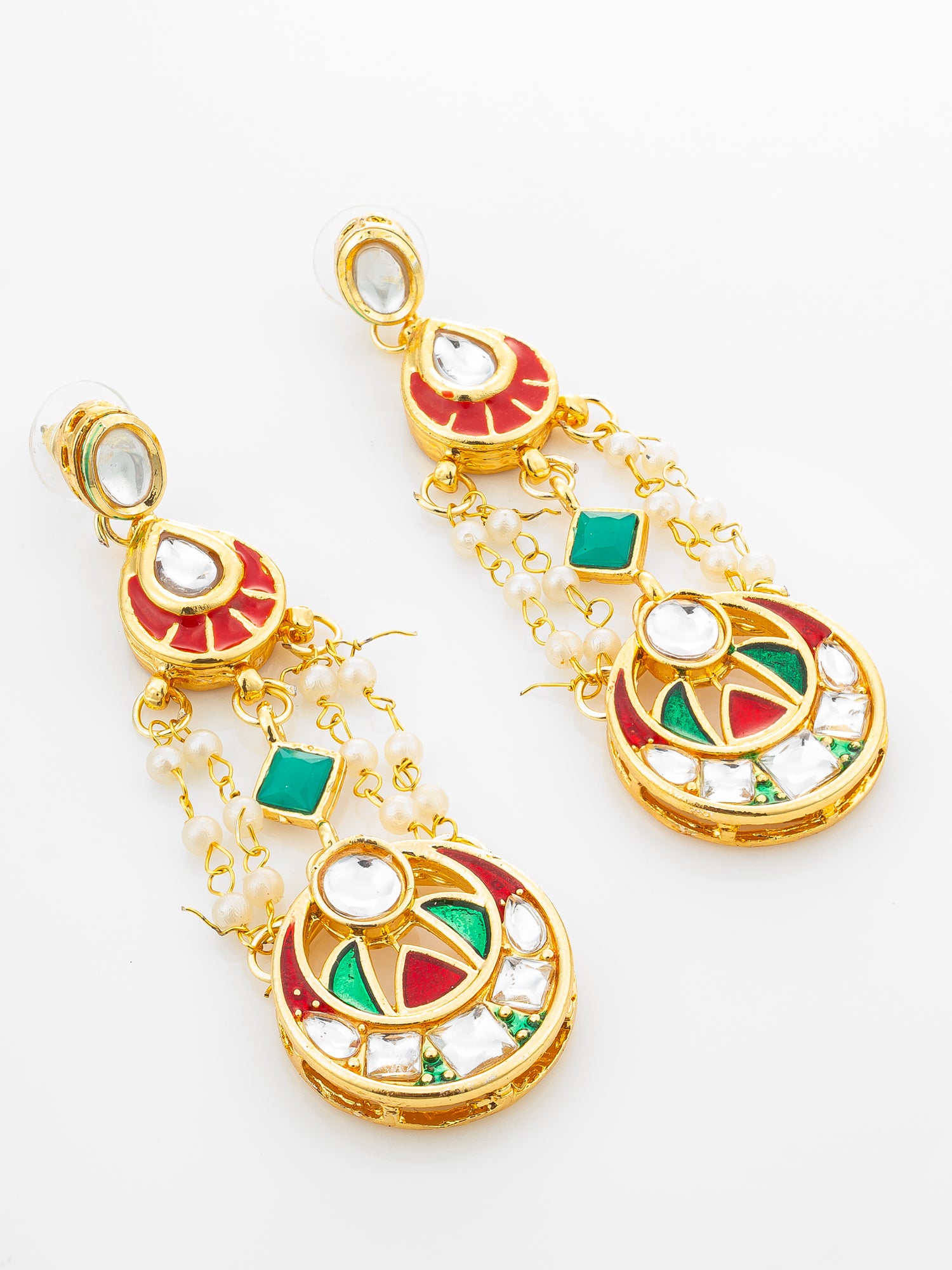 A pair of gold-plated Indian chandelier earrings decorated with red and green enamel, white faux pearls, and clear stones on a white background.