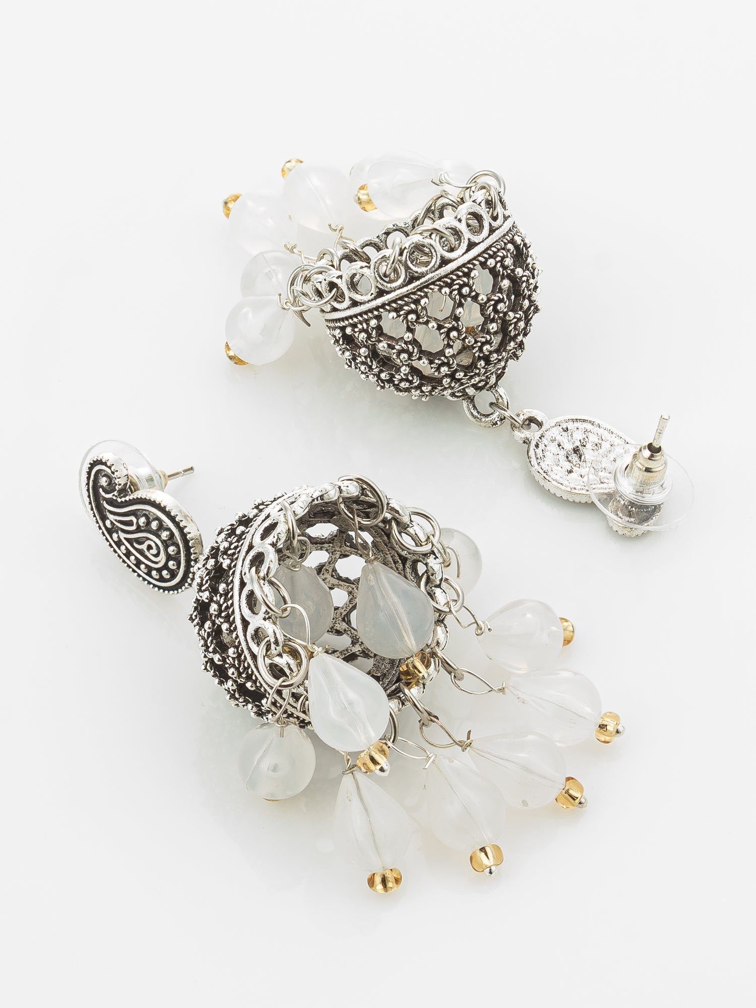 A pair of ornate silver-toned jhumka earrings decorated with white translucent beads, silver pavé detailing, and small gold bead accents, displayed on a clean white background.
