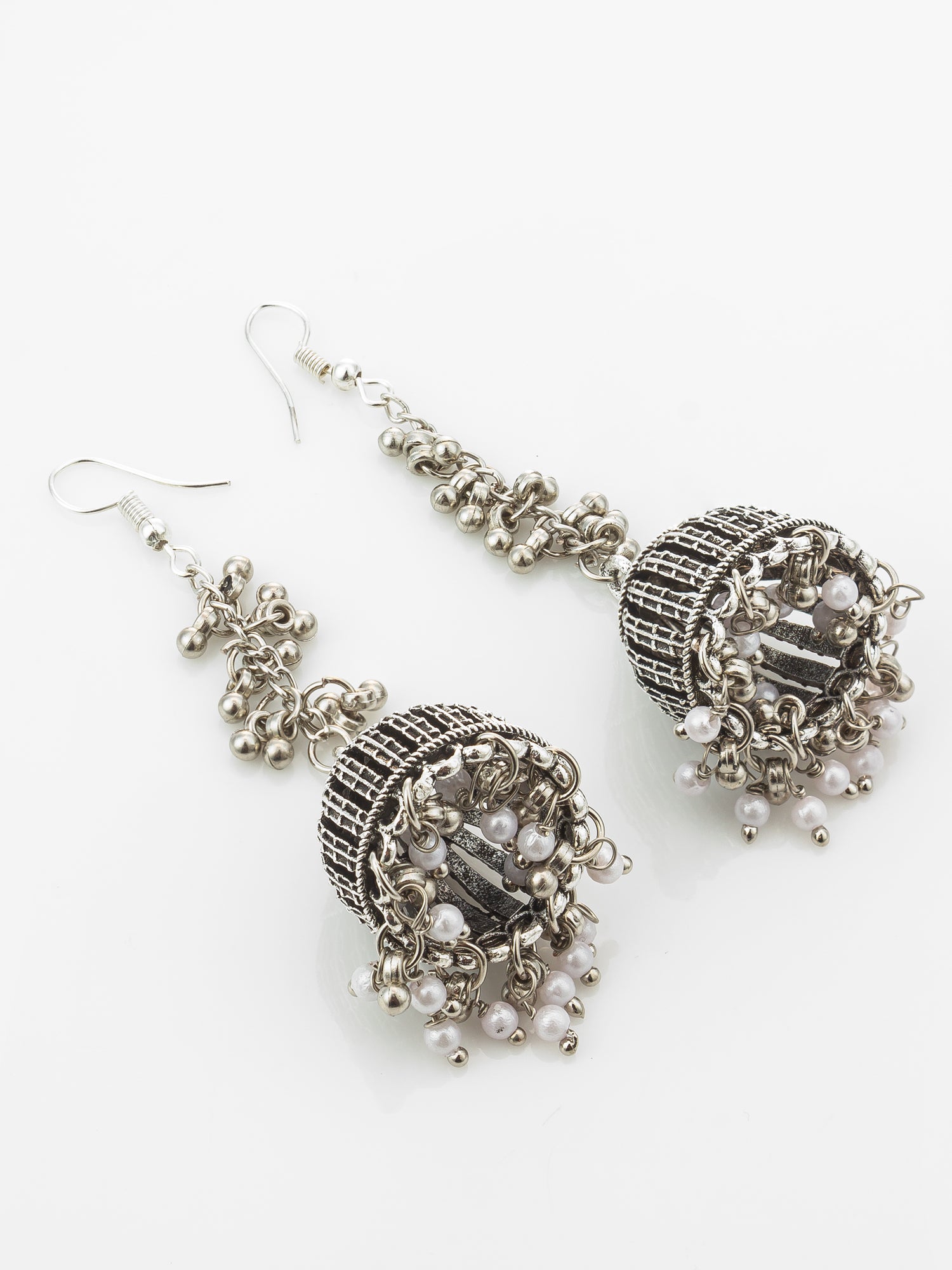 A pair of silver-toned jhumka earrings with intricate beadwork, textured metal detailing, and small white pearl-like beads, displayed on a clean white background.