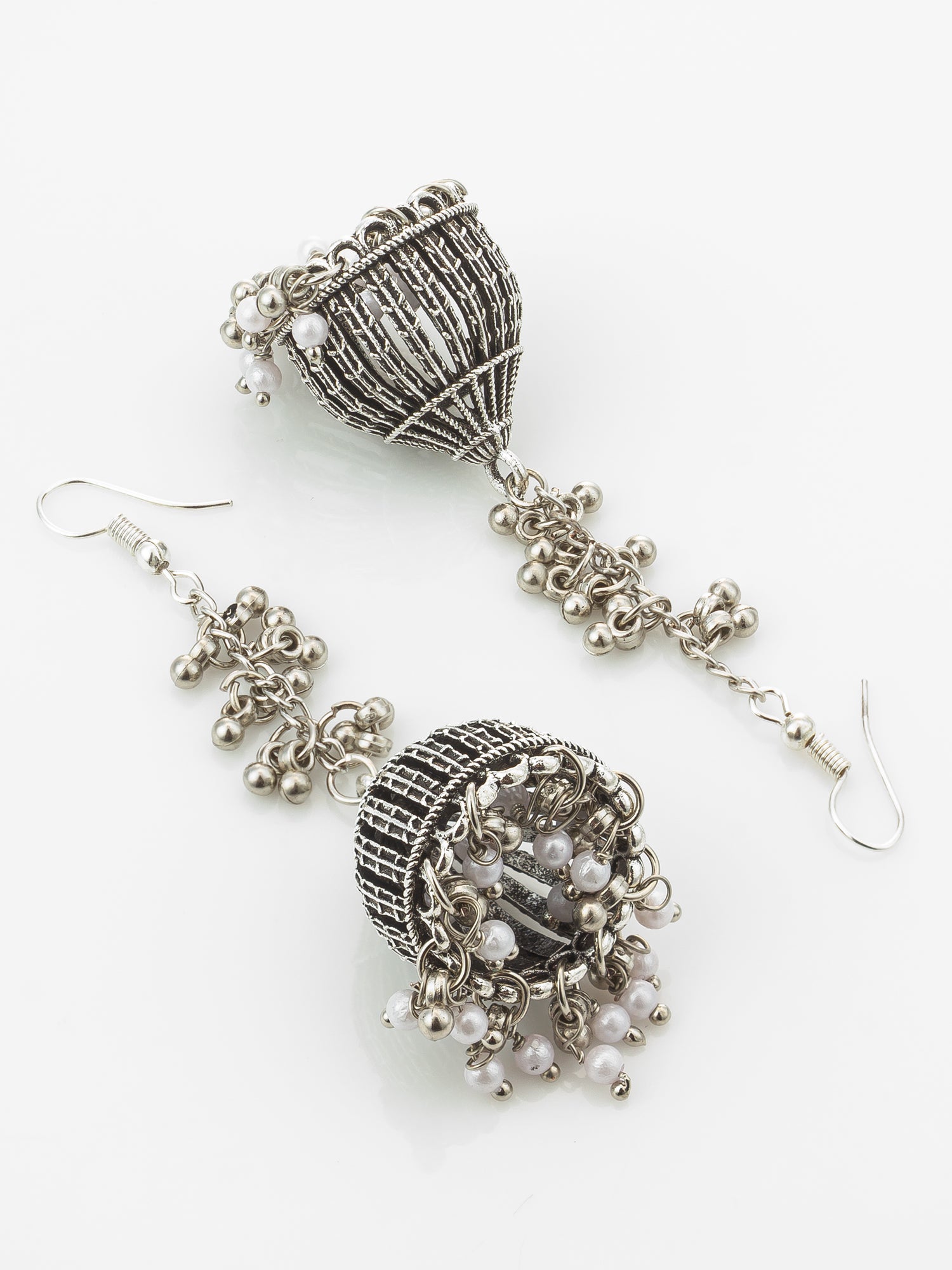 A pair of intricate silver-toned jhumka earrings with textured wirework, small metallic beads, and white pearl-like accents, displayed on a clean white background.